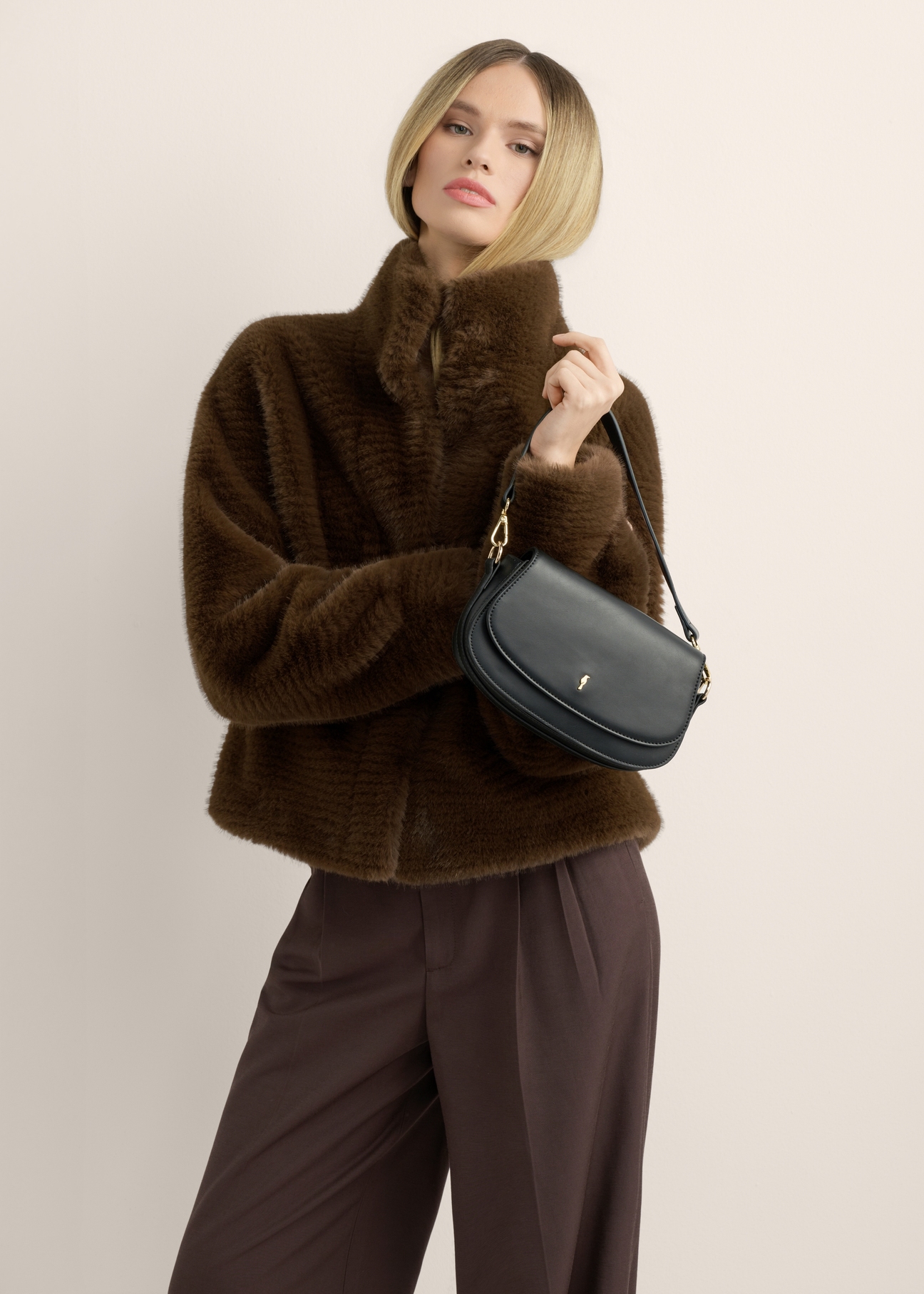 Small black women's handbag TOREC-1264-99(Z26), view of the product in the model's hand, on a light background.