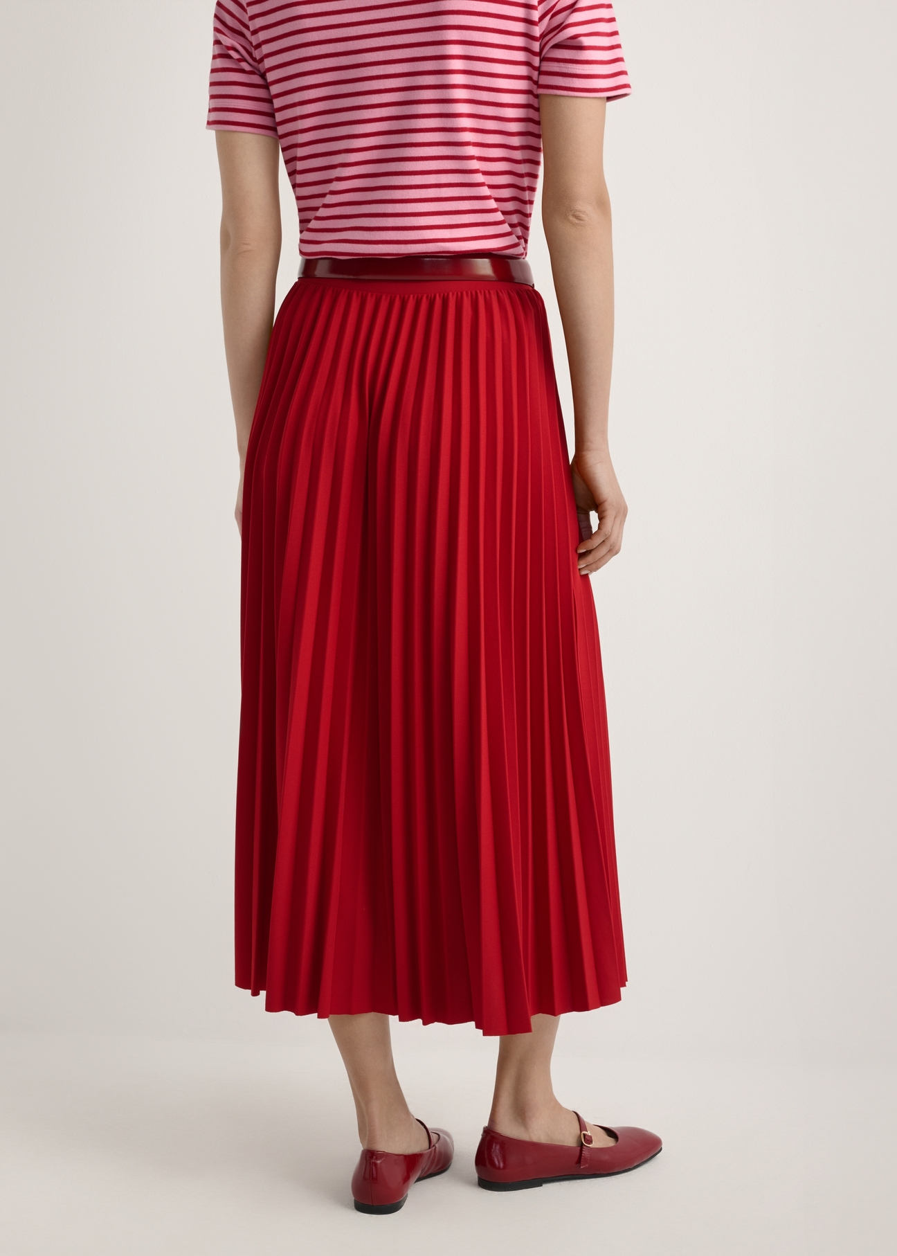 Red pleated midi skirt SPCDT-0096-4B(W26), product view from the back on the model, half of the silhouette visible.