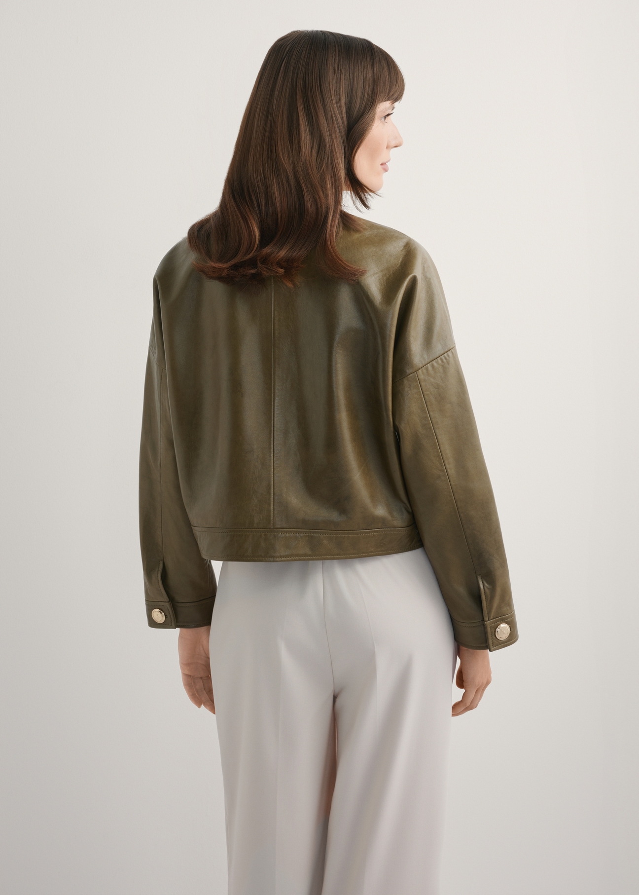 Women's khaki short leather jacket KURDS-0590-8D(W26), back view of the product on the model. Half of the silhouette visible.
