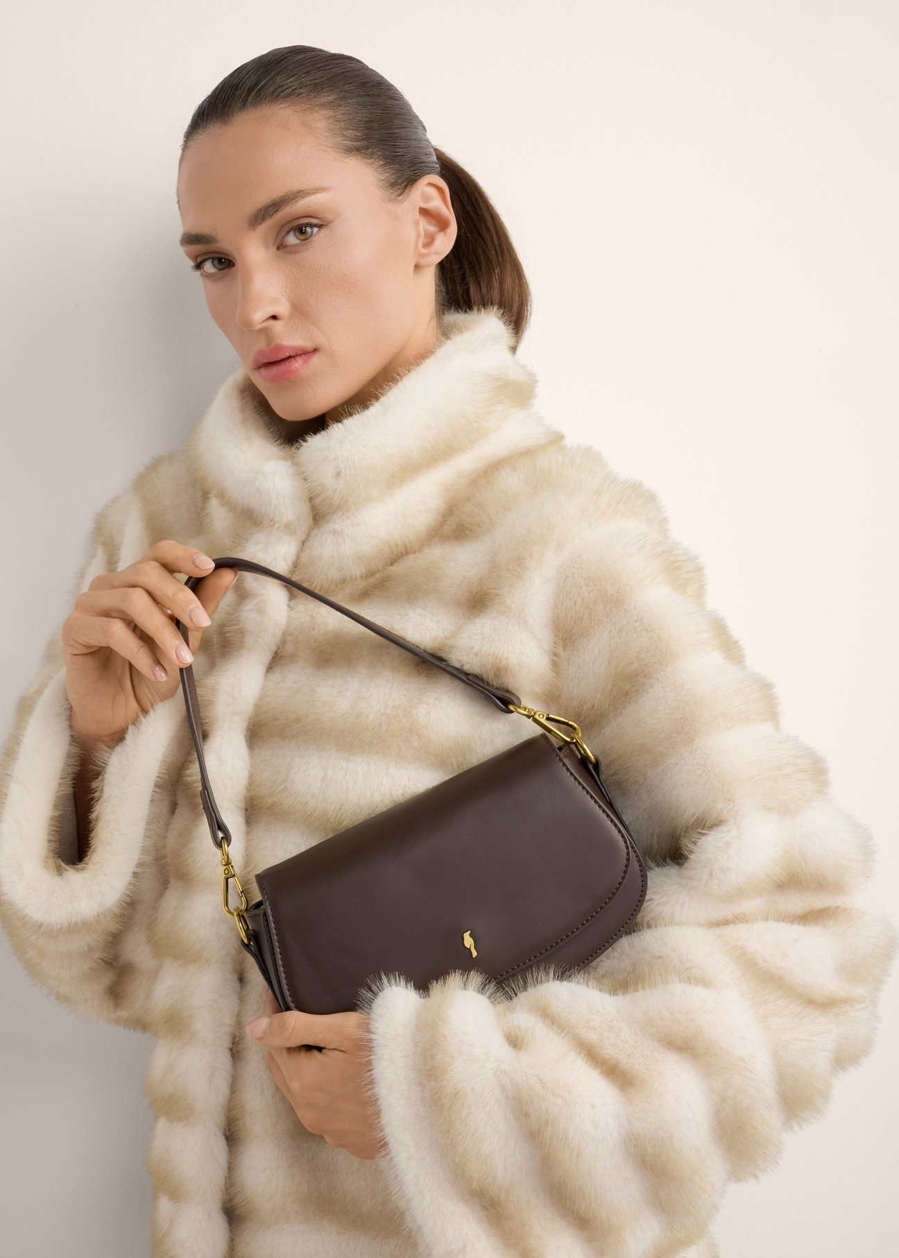 Small brown women's handbag TOREC-1264-1I(Z26), view of the product in the model's hands, on a light background.