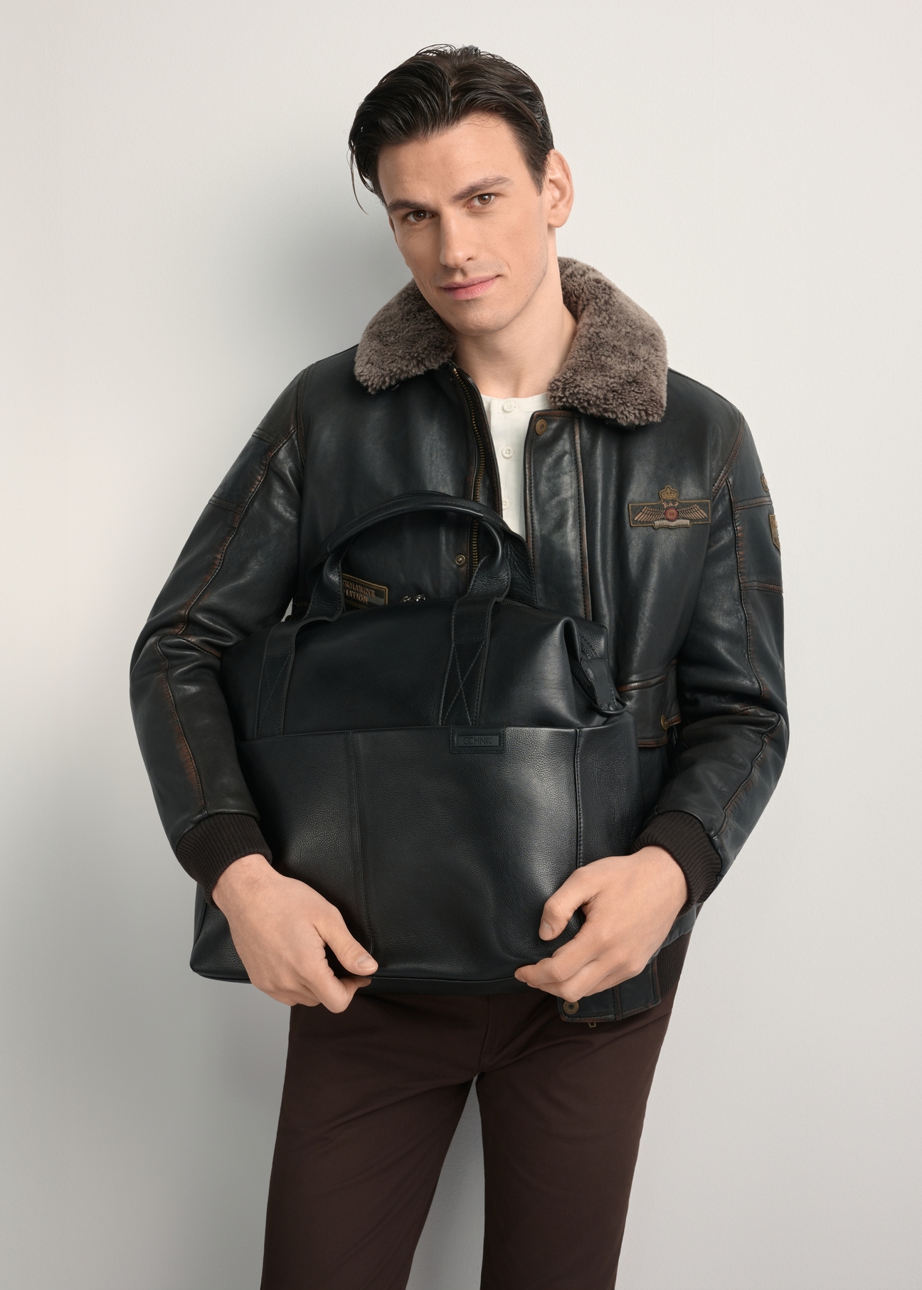 Men's black leather travel bag TORMS-0421A-99(Z25) - front view of the product, held by the model. Half of the silhouette visible.