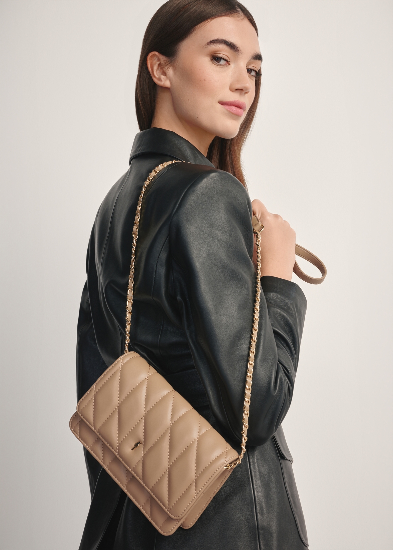 Small quilted women's handbag in beige color TOREC-1150-1D(W26), front view of the product on the model, half of the silhouette visible.