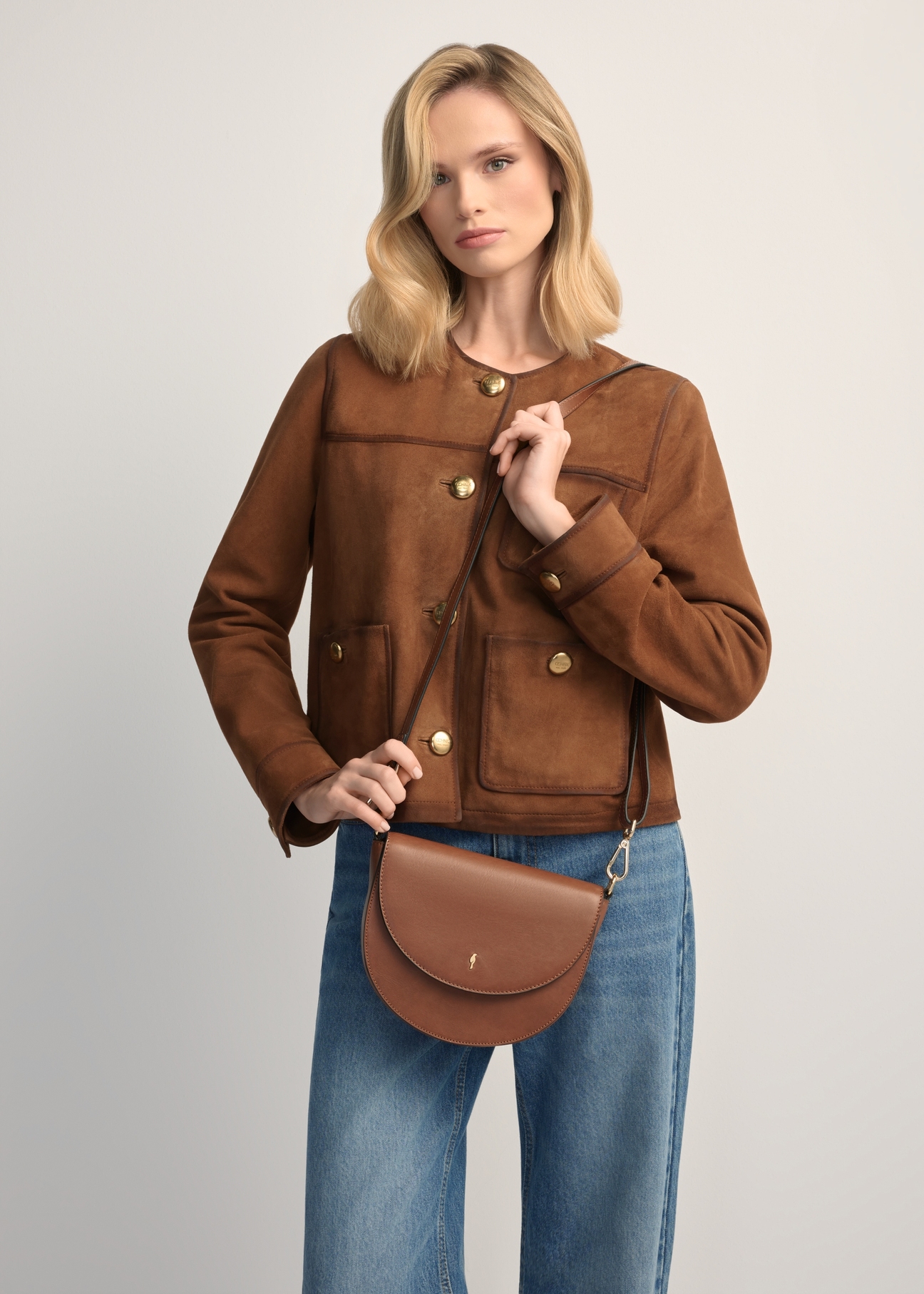Women's brown leather messenger bag TORES-1246-1F(W26), product view in model's hands. Half silhouette visible.