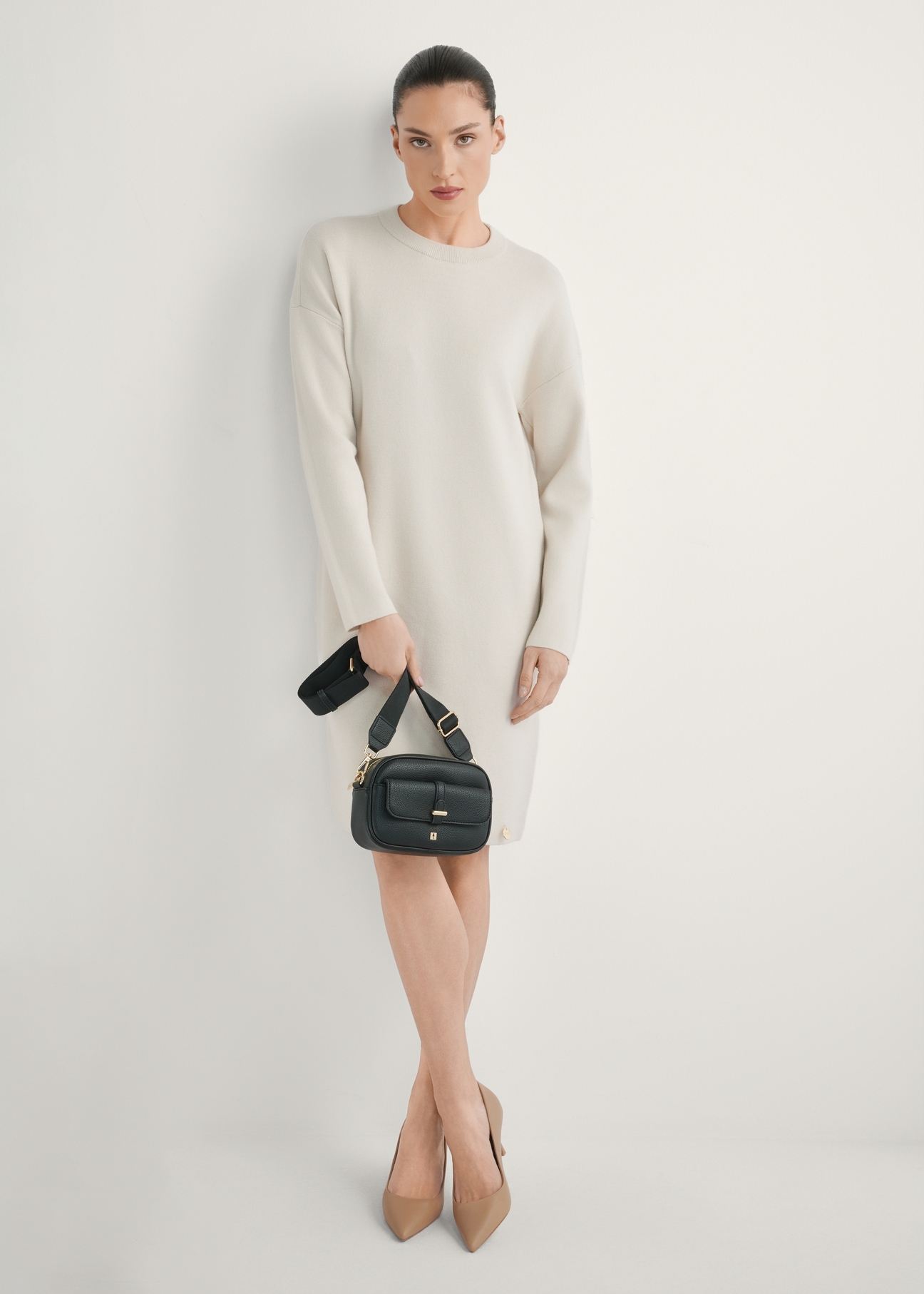 Small black women's handbag TOREC-1174-99(W26), view of the product in the model's hand. Full body visible.