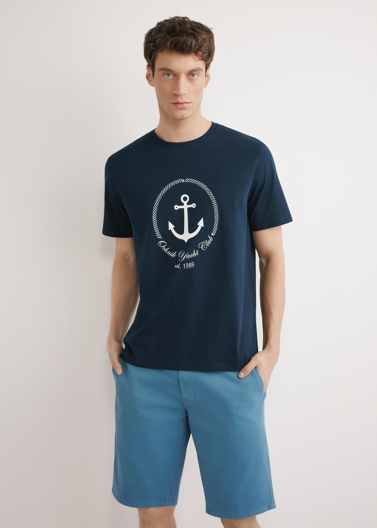 Navy blue men's T-shirt with print TSHMT-0147-7E(W26), front view of the product, on a model, against a light background. Half of the silhouette visible.