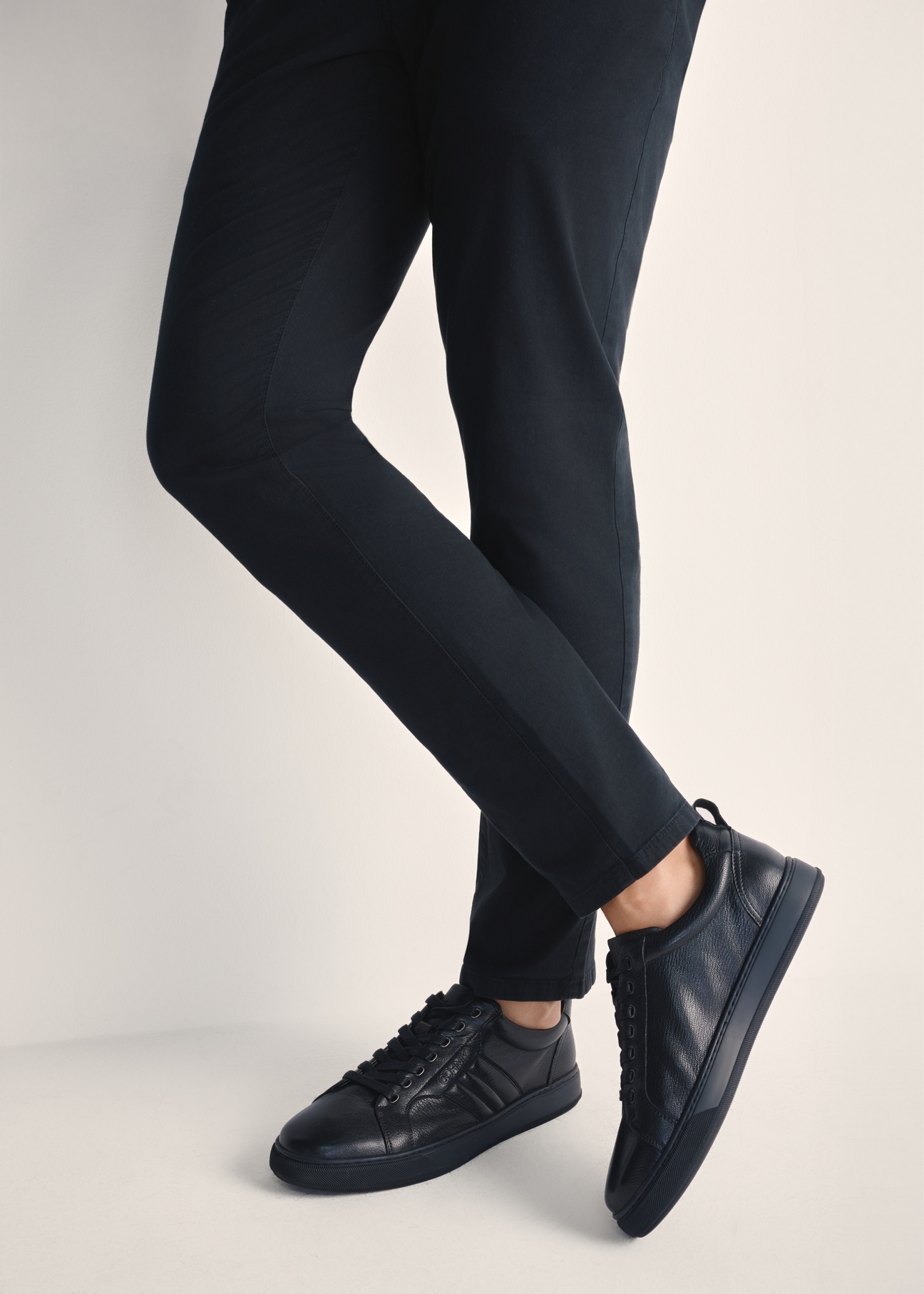 Black men's leather sneakers BUTYM-0465-99(Z25), product view on model's feet against a light background.