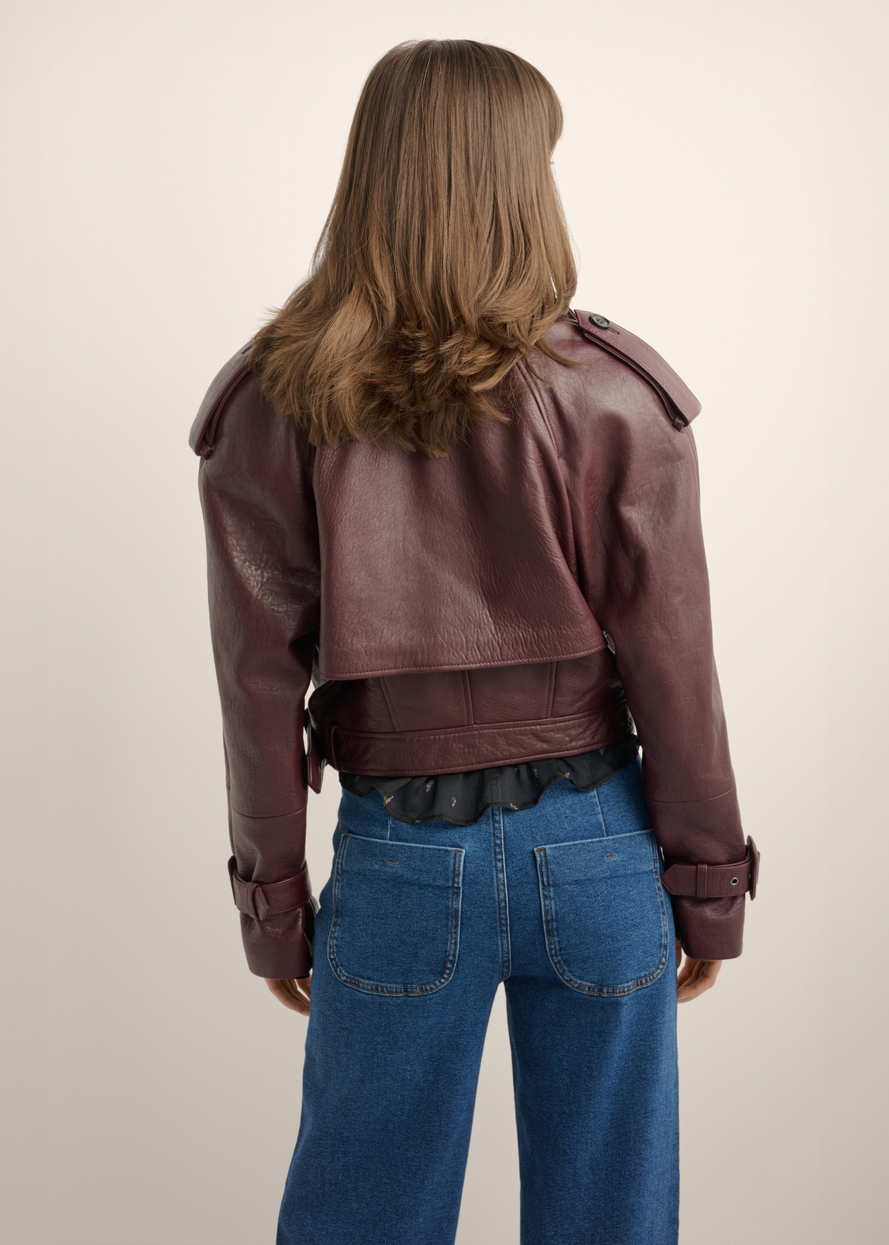 Burgundy women's short leather jacket KURDS-0615-4E(Z26), product view from the back on the model. Half of the silhouette visible.