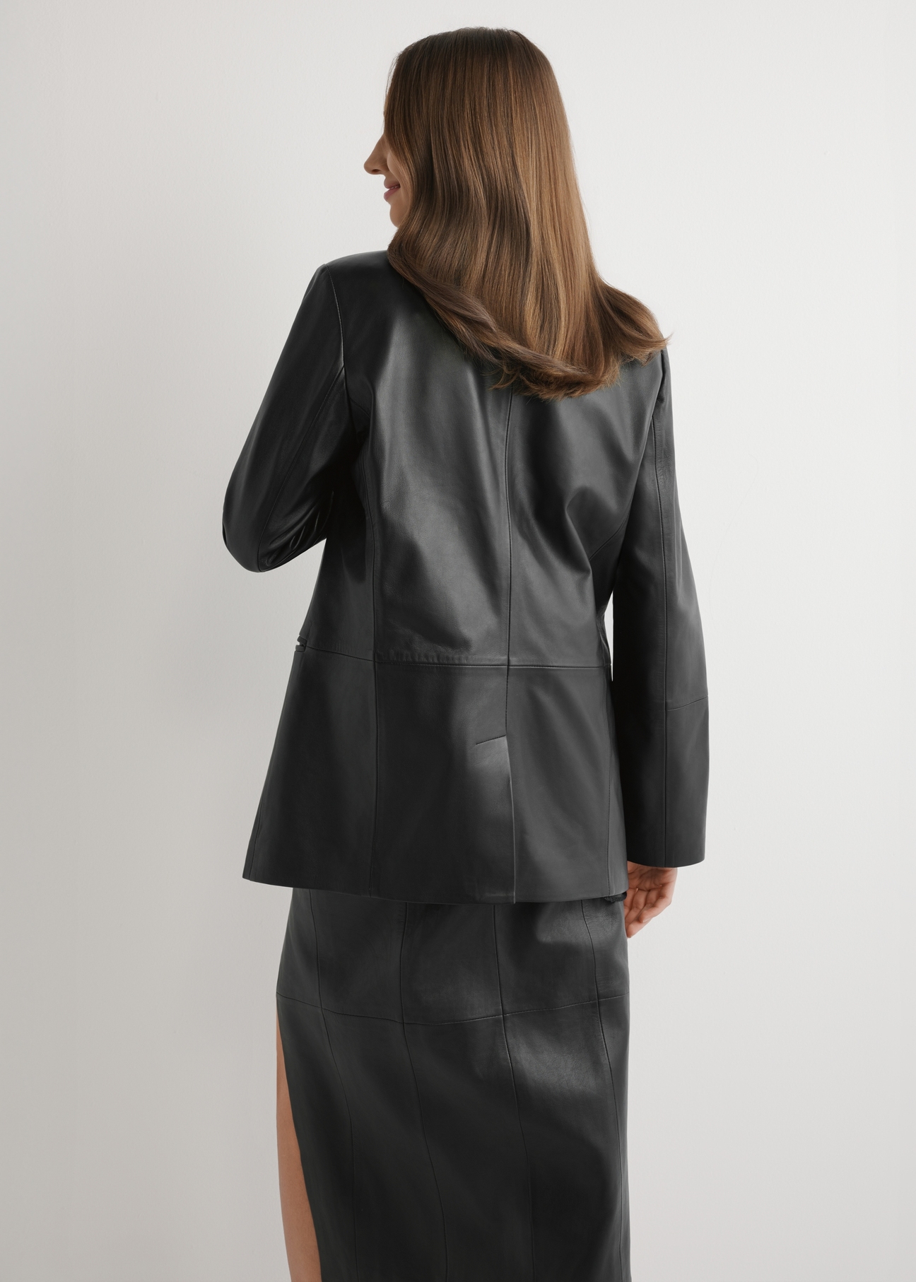 Women's black leather jacket KURDS-0606-99(W26) - back view of the product on a model, against a light background. Knee-length silhouette visible.