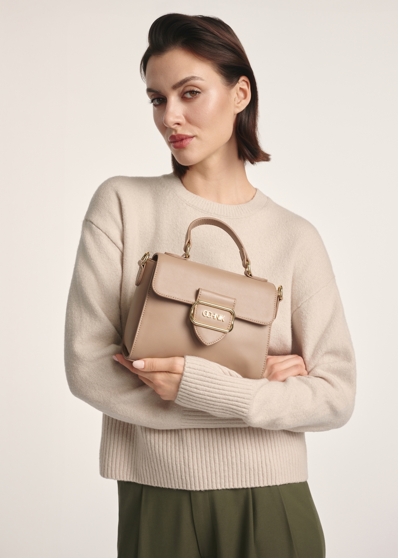 Beige small women's shoulder bag TOREC-0962A-81(Z25), product view in model's hands. Half of silhouette visible.