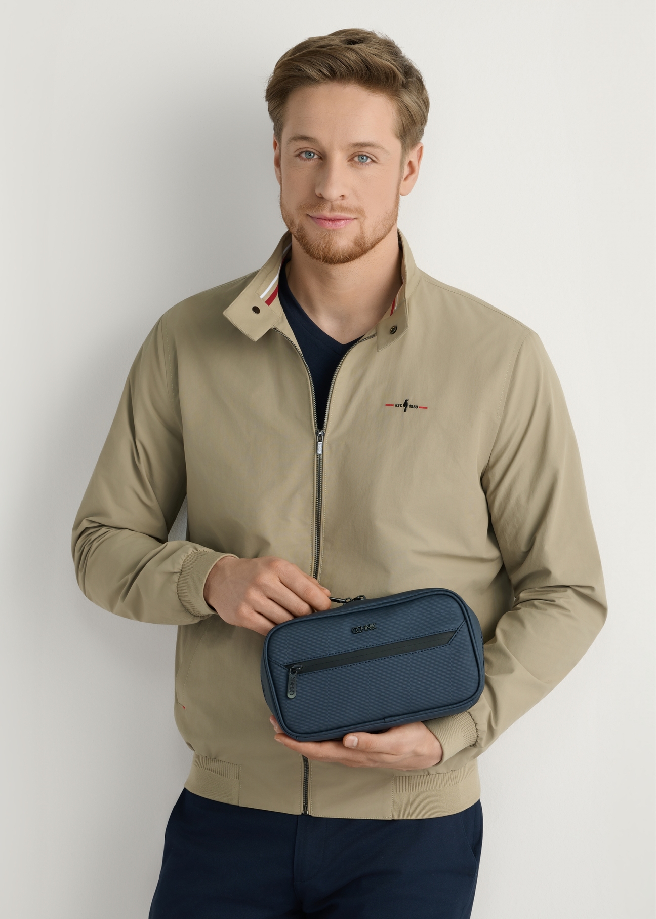 Navy blue men's cosmetic bag TORMN-0413-7D(W26), front view of the product in the model's hands. Half of the silhouette visible.