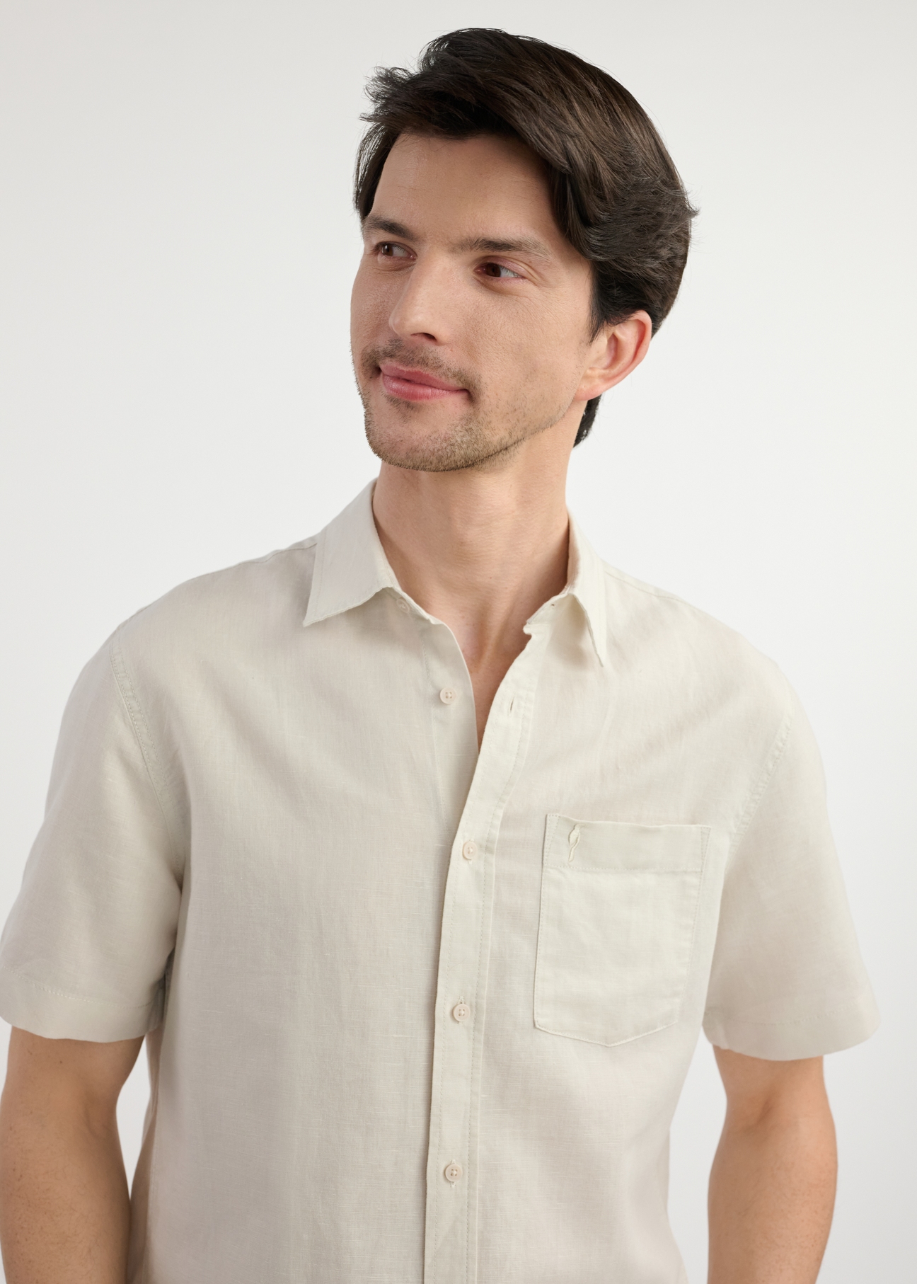 Beige men's shirt with short sleeves KOSMT-0327-81(W25) - close-up of the front on the model on a white background. Half of the silhouette visible.