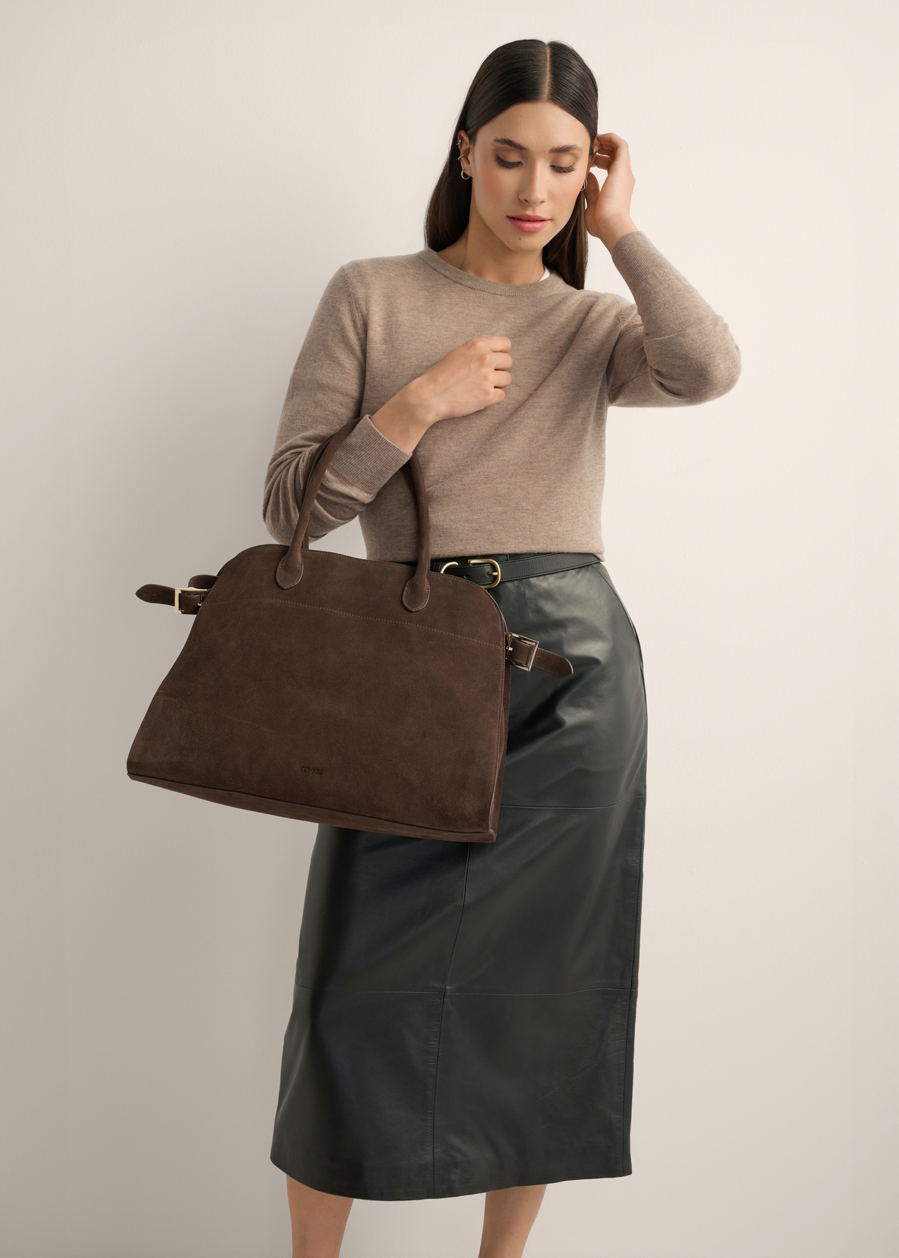 Dark brown leather shopper bag TORES-1412-1H(Z26) - a slightly diagonal view of the bag, held by the model, against a light background. The knee-length silhouette is visible.