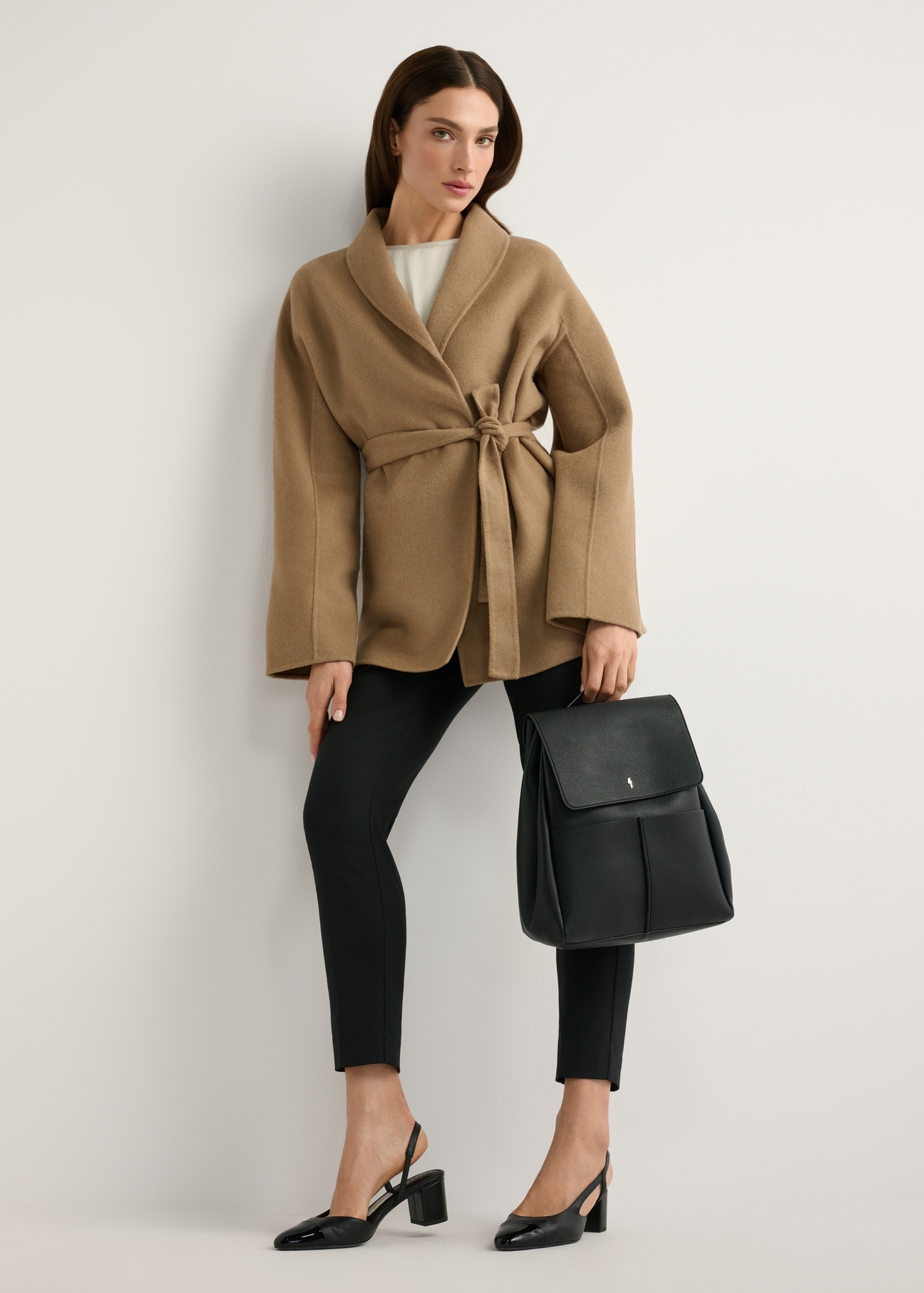 Black medium women's backpack TOREC-1132-99(W26) - front view of the product, held by the model, against a light background. The entire silhouette is visible.