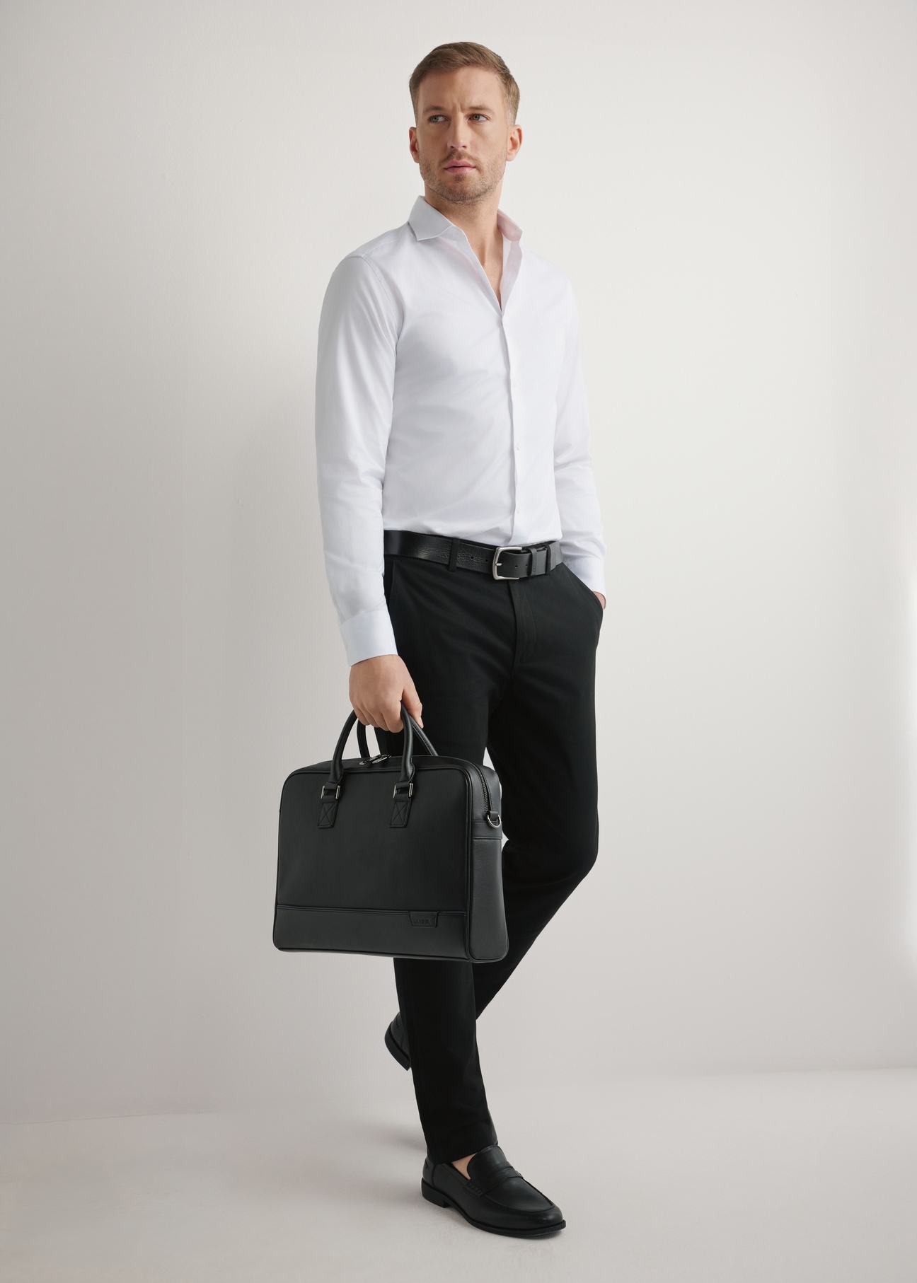 Black leather laptop bag TORMS-0494-99(W26) - slightly diagonal view of the product, held in the model's hand, against a light background.