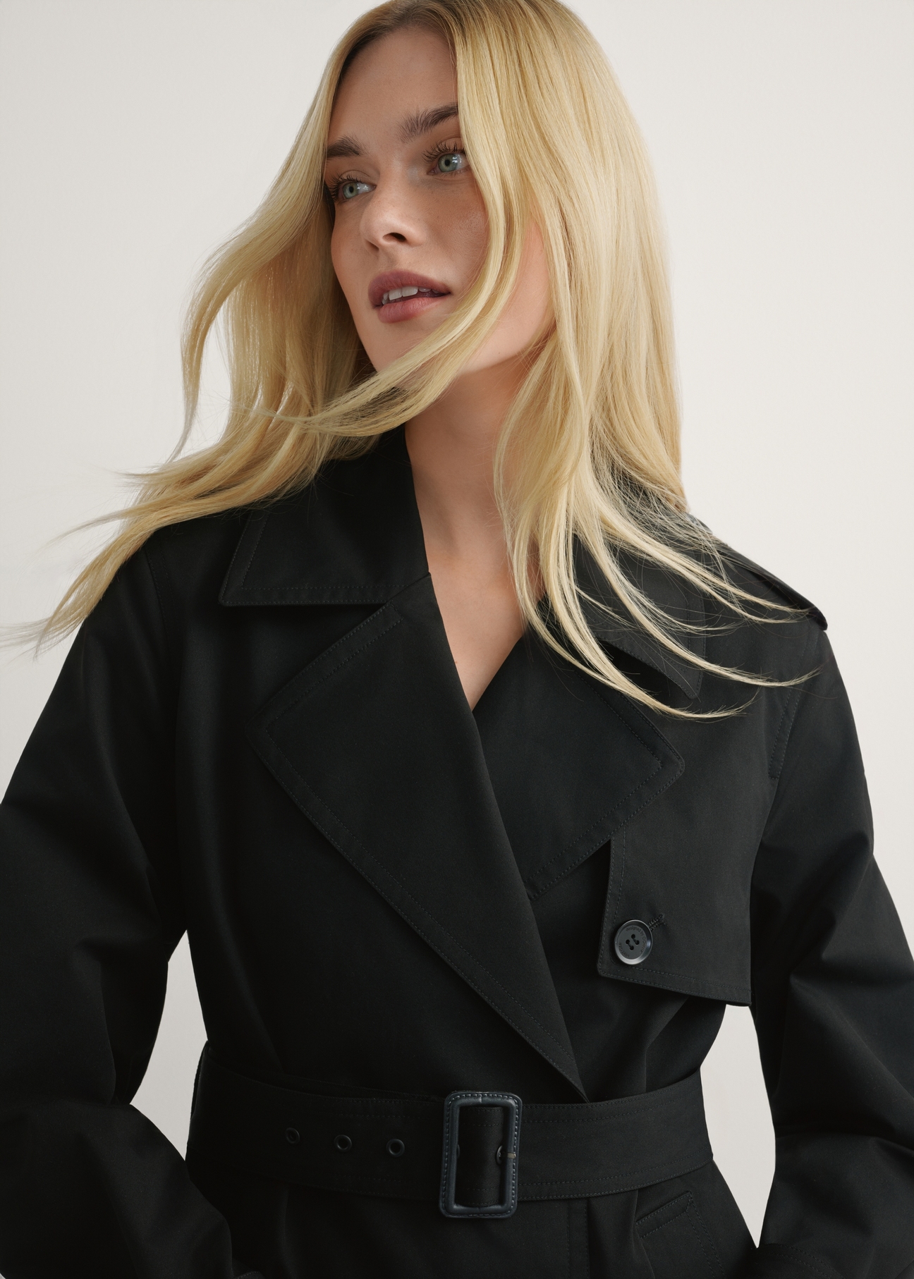 Long black women's jacket in the form of a coat KURDT-0512-99(W25), product view from the front on the model, half of the silhouette visible.