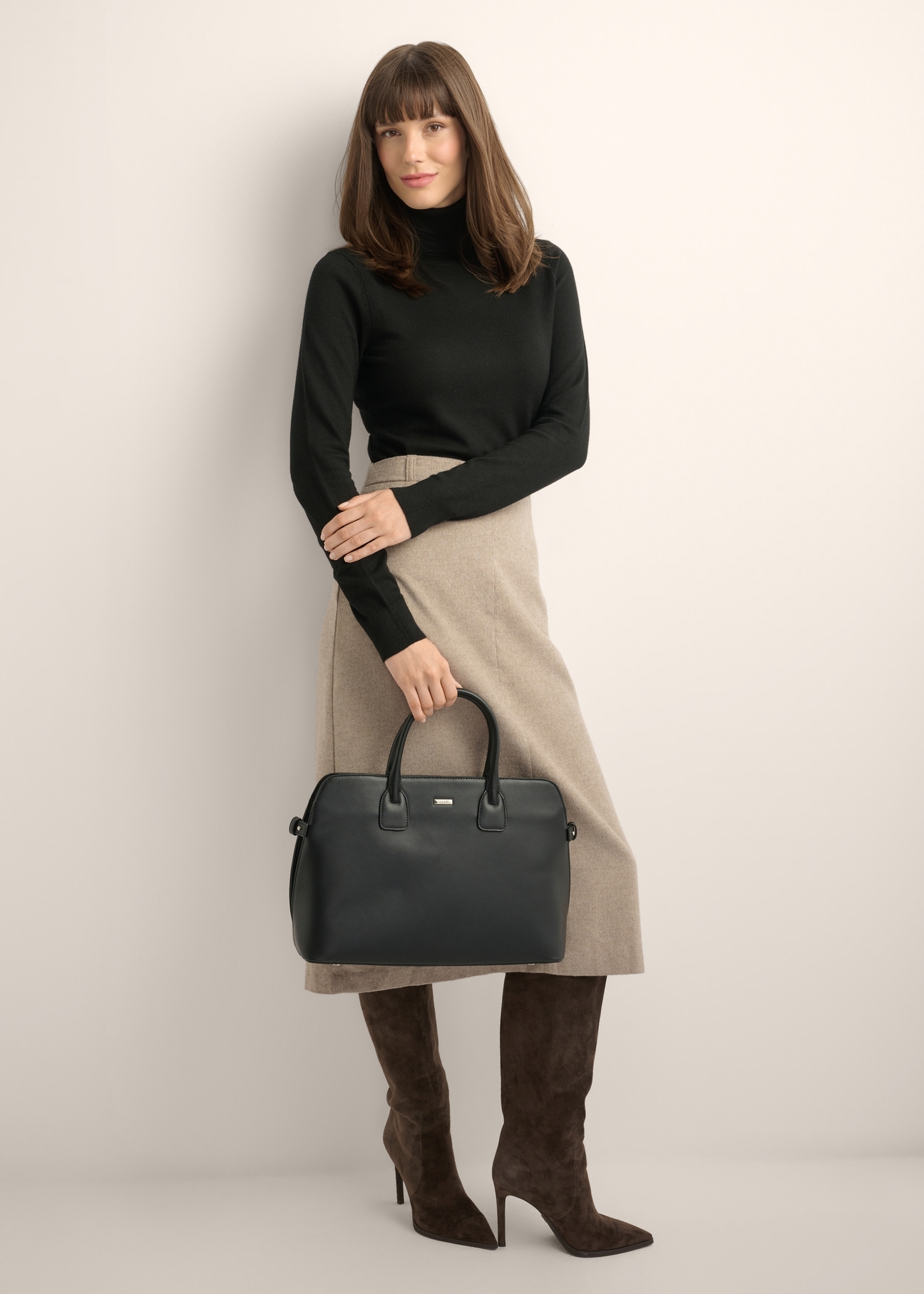 Black women's laptop bag TOREC-1351-99(Z26) - front view of the product, held by the model, against a light background. The entire silhouette is visible.