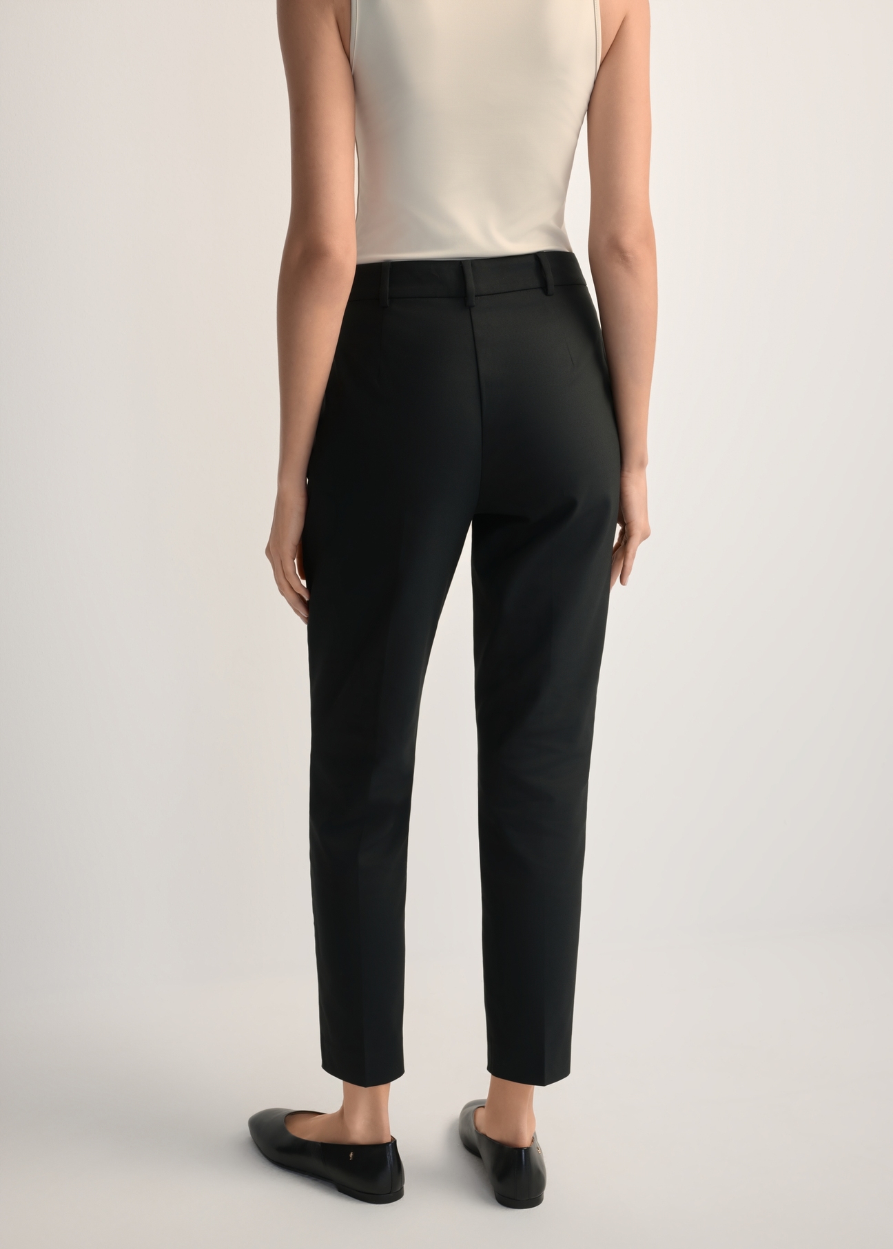 Women's black pleated trousers SPODT-0090-99(W25), back view of the product on the model. Half of the silhouette visible.