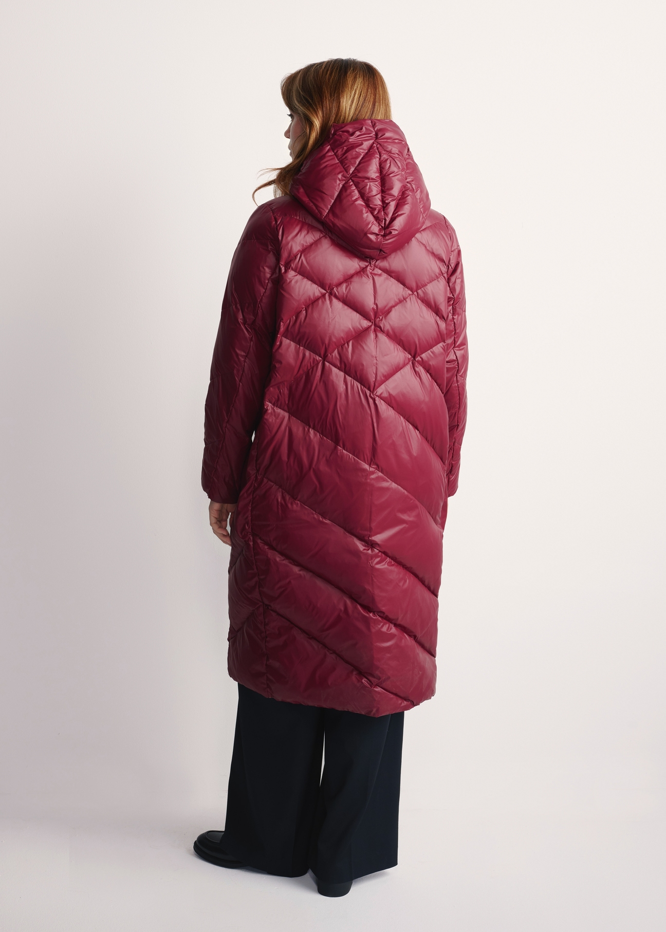 Long burgundy women's winter jacket KURDT-0542A-49(Z25), back view of the product on the model, the whole silhouette is visible.