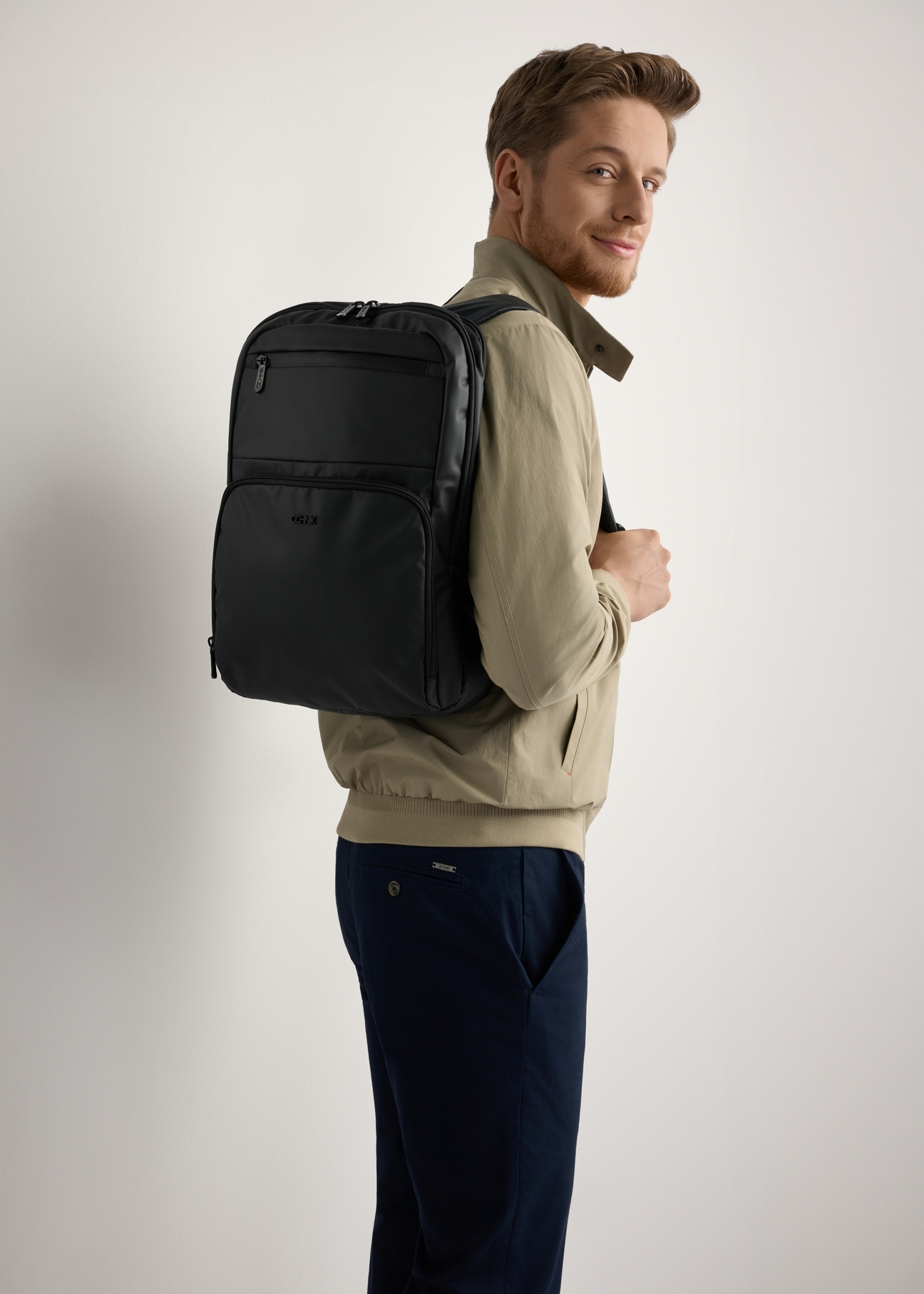 Black men's backpack TORMS-0410-99(W26) - side view of the product, on a model, against a light background. Knee-length silhouette visible.