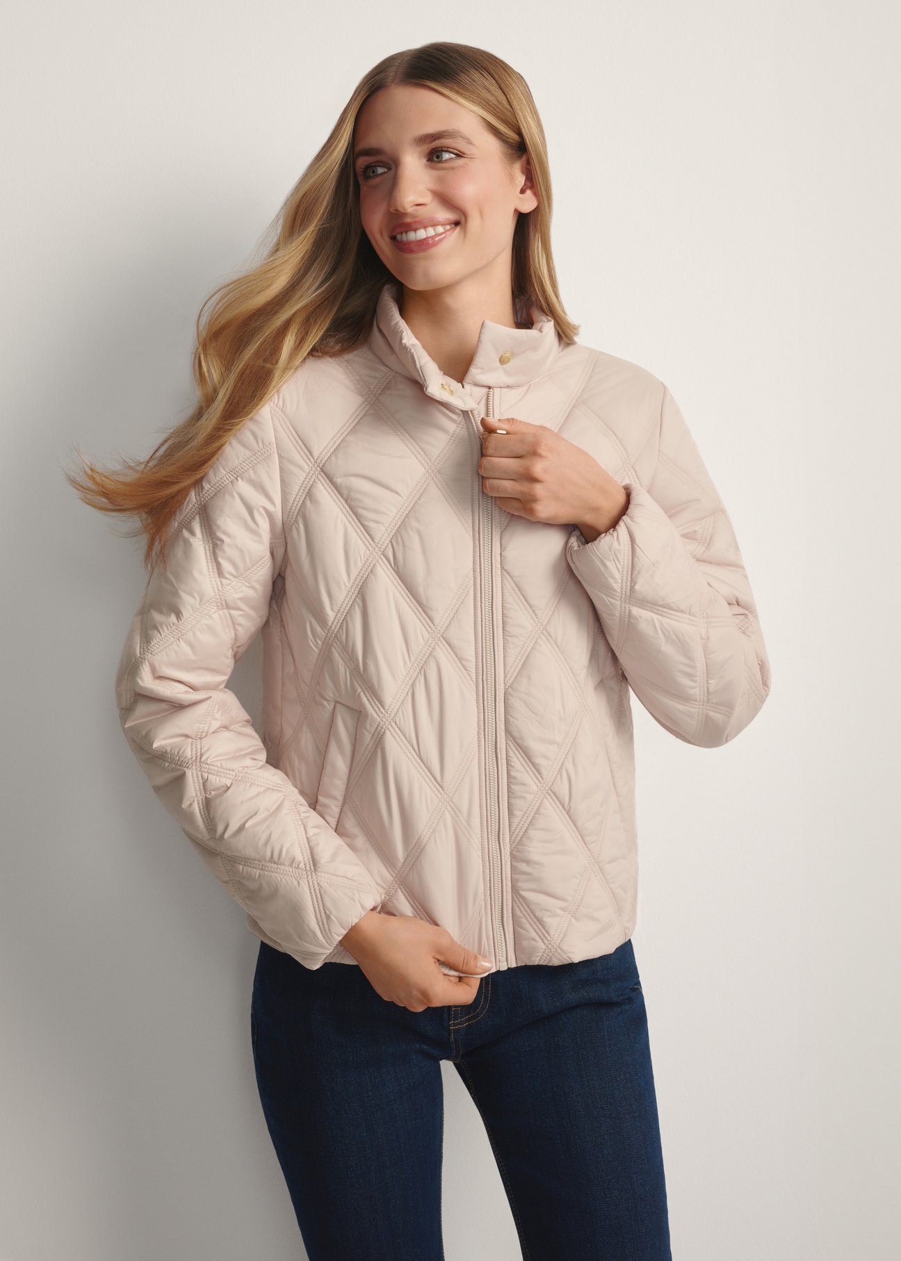Beige women's quilted jacket KURDT-0658-1A(W26), front view of the buttoned-up product on the model. Half of the silhouette visible.