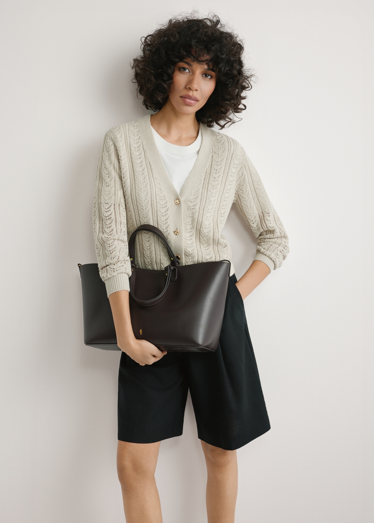 Brown women's shopper bag TOREC-1240-1H(W26), product view in model's hands. Half of silhouette visible.