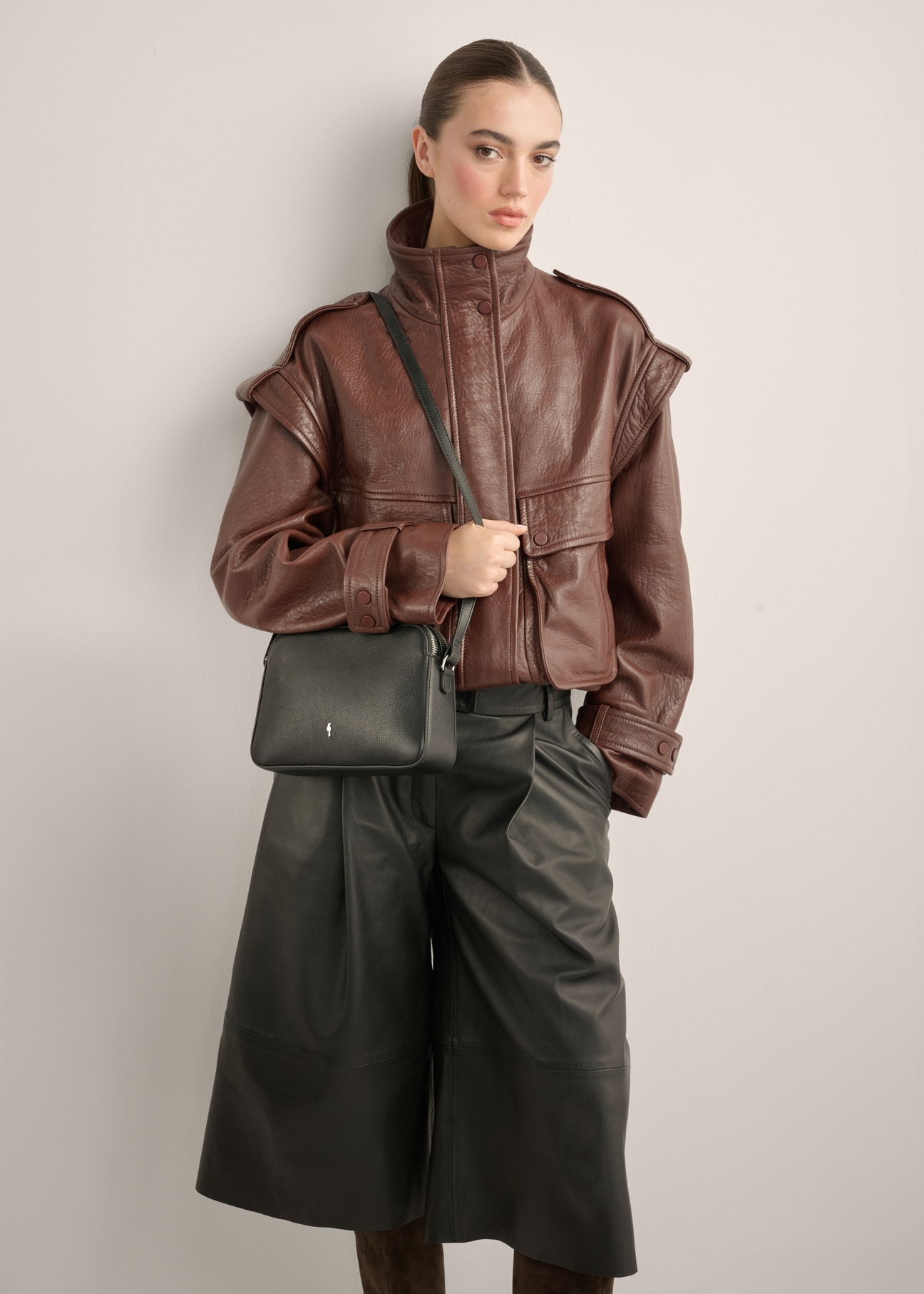Small black leather women's handbag TORES-1353-99(Z26), diagonal view of the product on the model. Half of the silhouette visible.