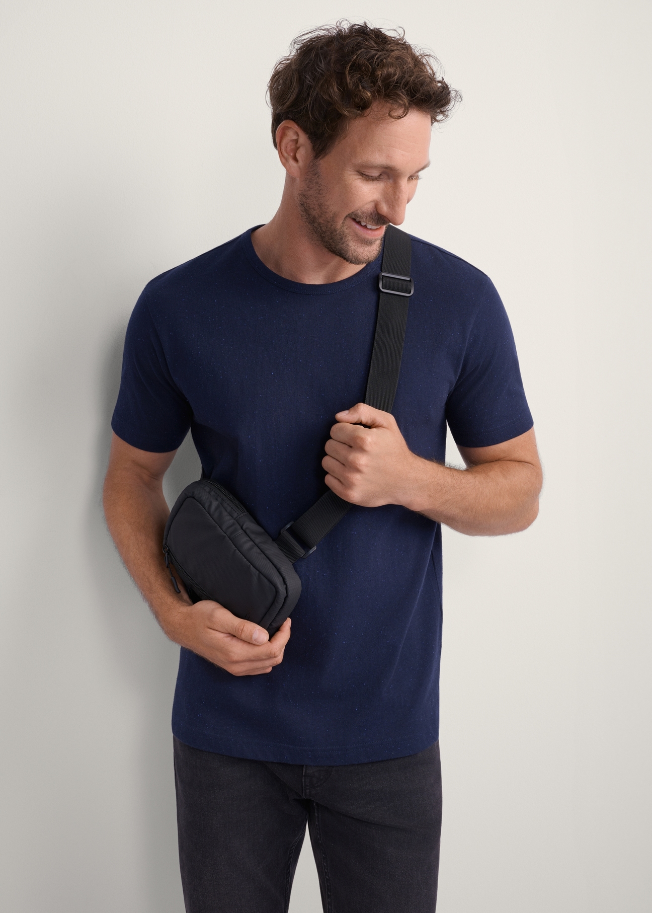 Small black men's pouch TORMN-0363-99(Z25), front view of the product on the model. Half of the silhouette visible.