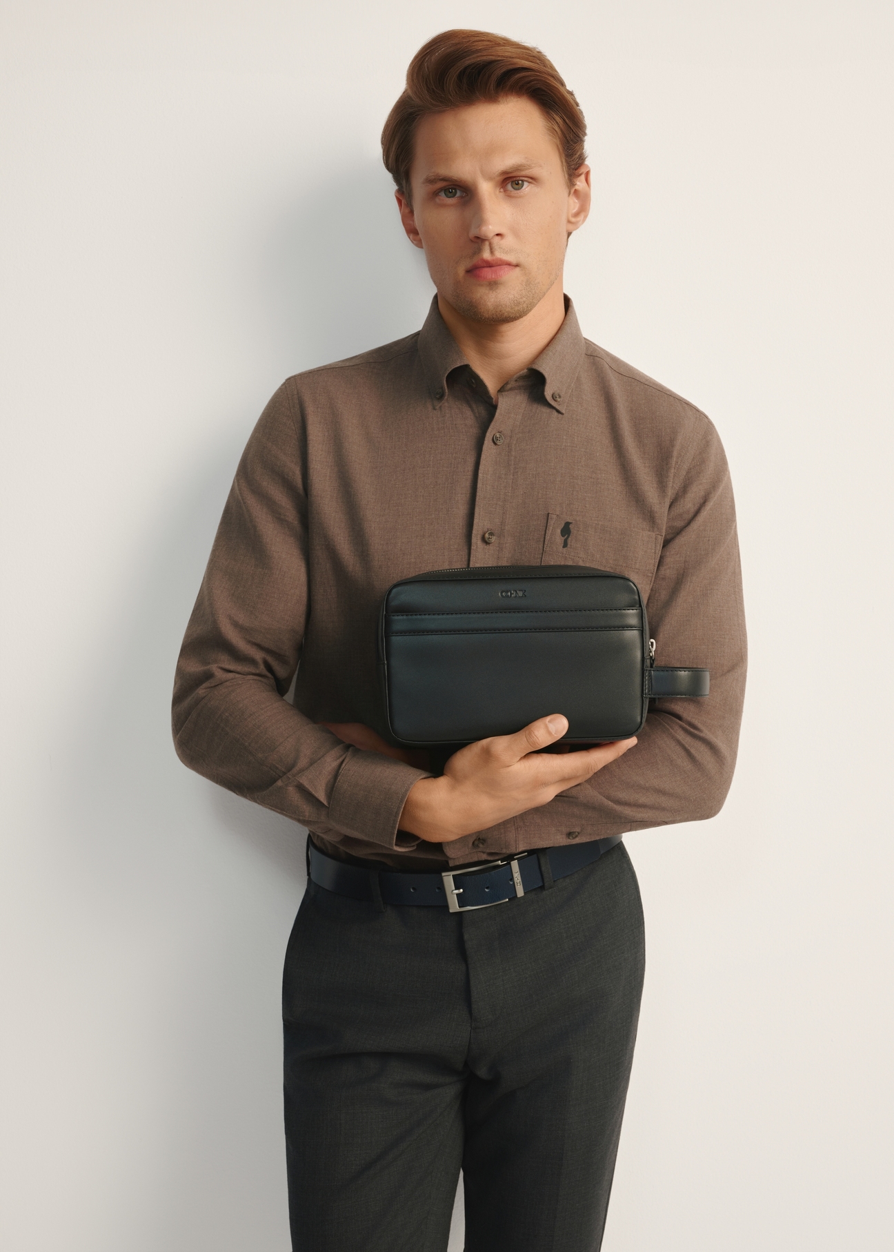 Black leather men's cosmetic bag TORMS-0473-99(Z25), front view of the product on the model, half of the silhouette visible.