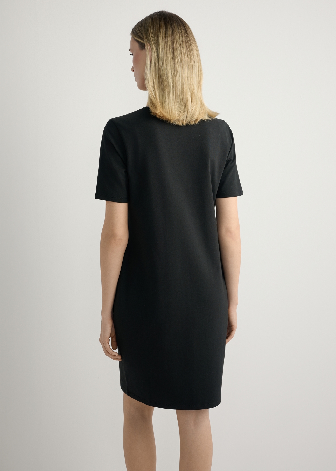 Black cotton dress SUKDT-0185A-99(W26), back view of the product on the model. Half of the silhouette visible.