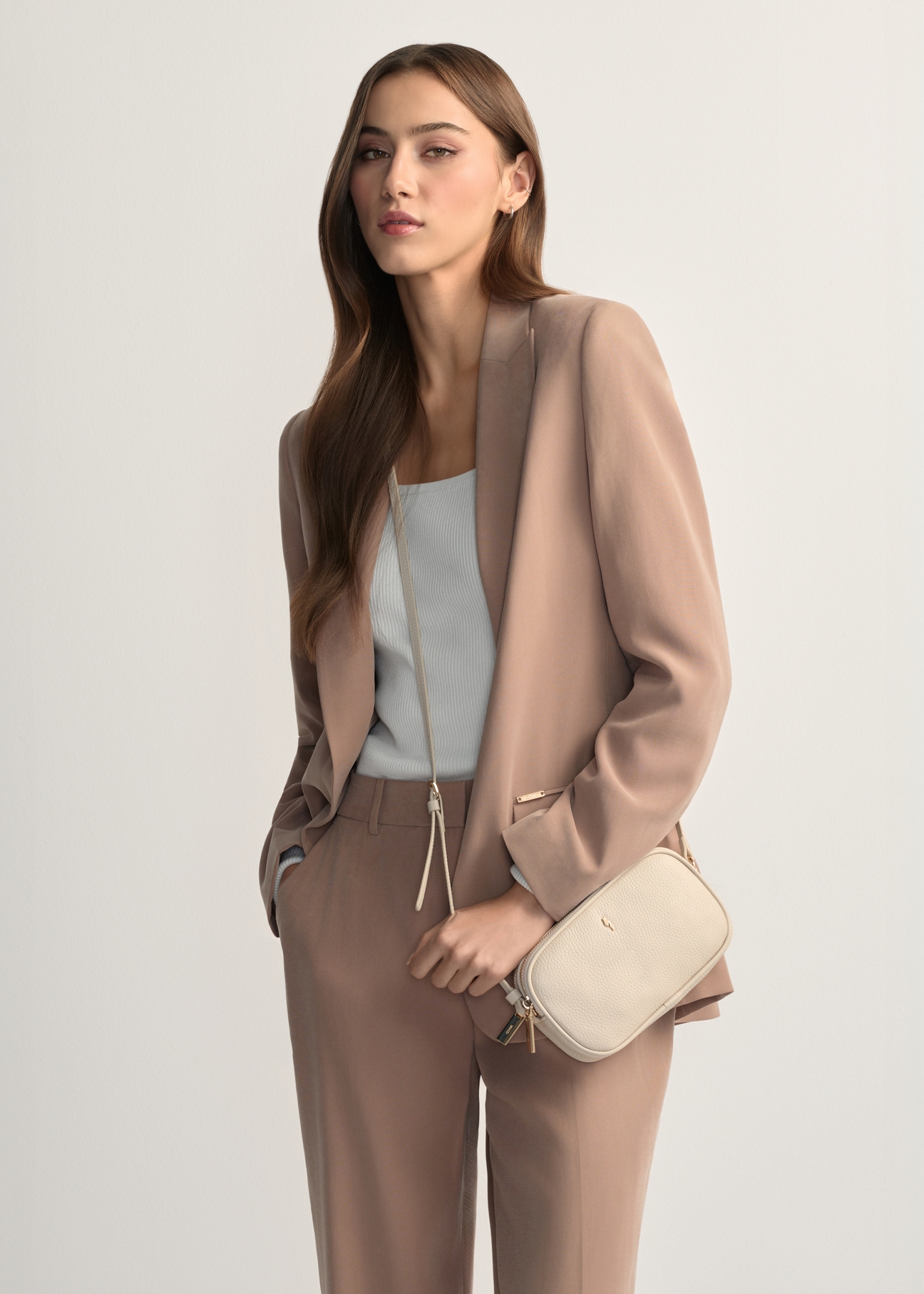 Small women's leather handbag in cream color TORES-1152-0B(W26), product view from the front on the model, half of the silhouette visible.