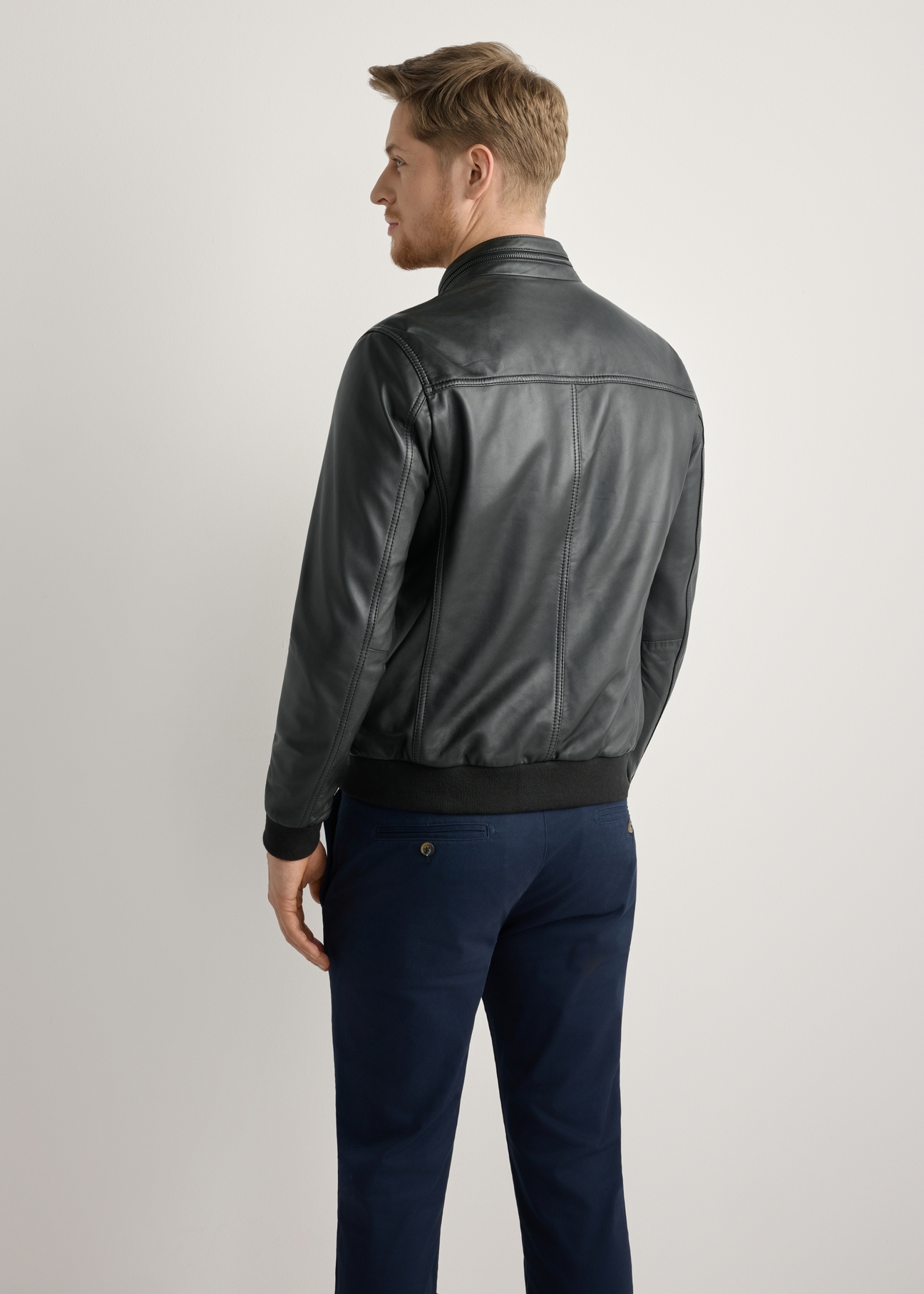 Men's black leather jacket KURMS-0392-99(W26) - back view of the product, on a model, against a light background. Knee-length silhouette visible.