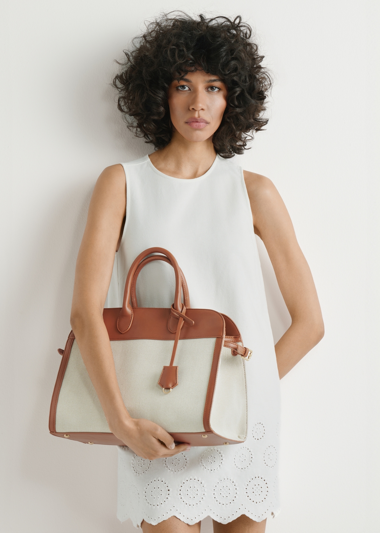 Beige large women's handbag TOREC-1202-0P(W26) - front view of the product, held by the model, against a light background. Half of the silhouette is visible.