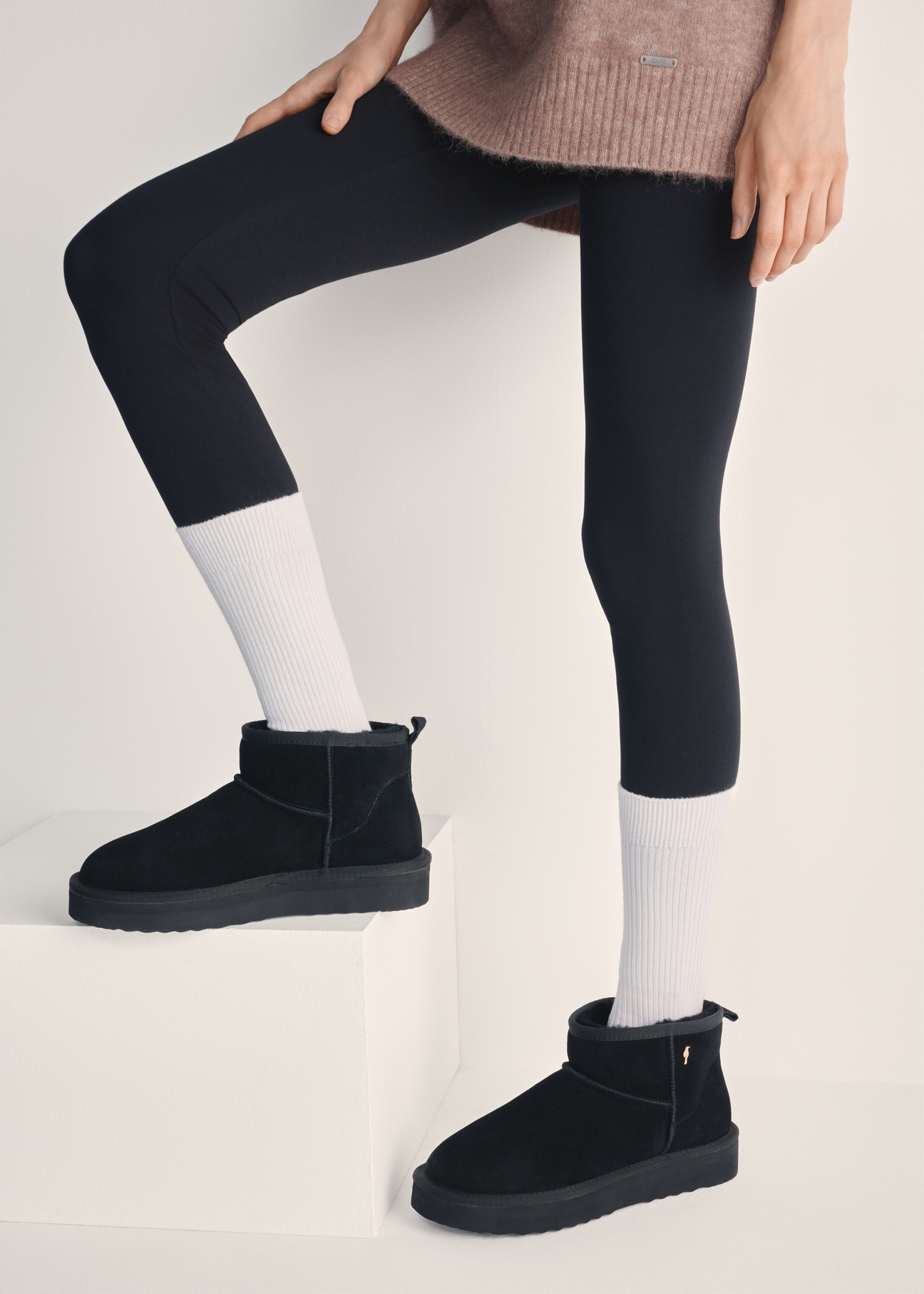 Black short women's snow boots BUTYD-1138-99(Z25), view of the product on the model's feet against a light background.