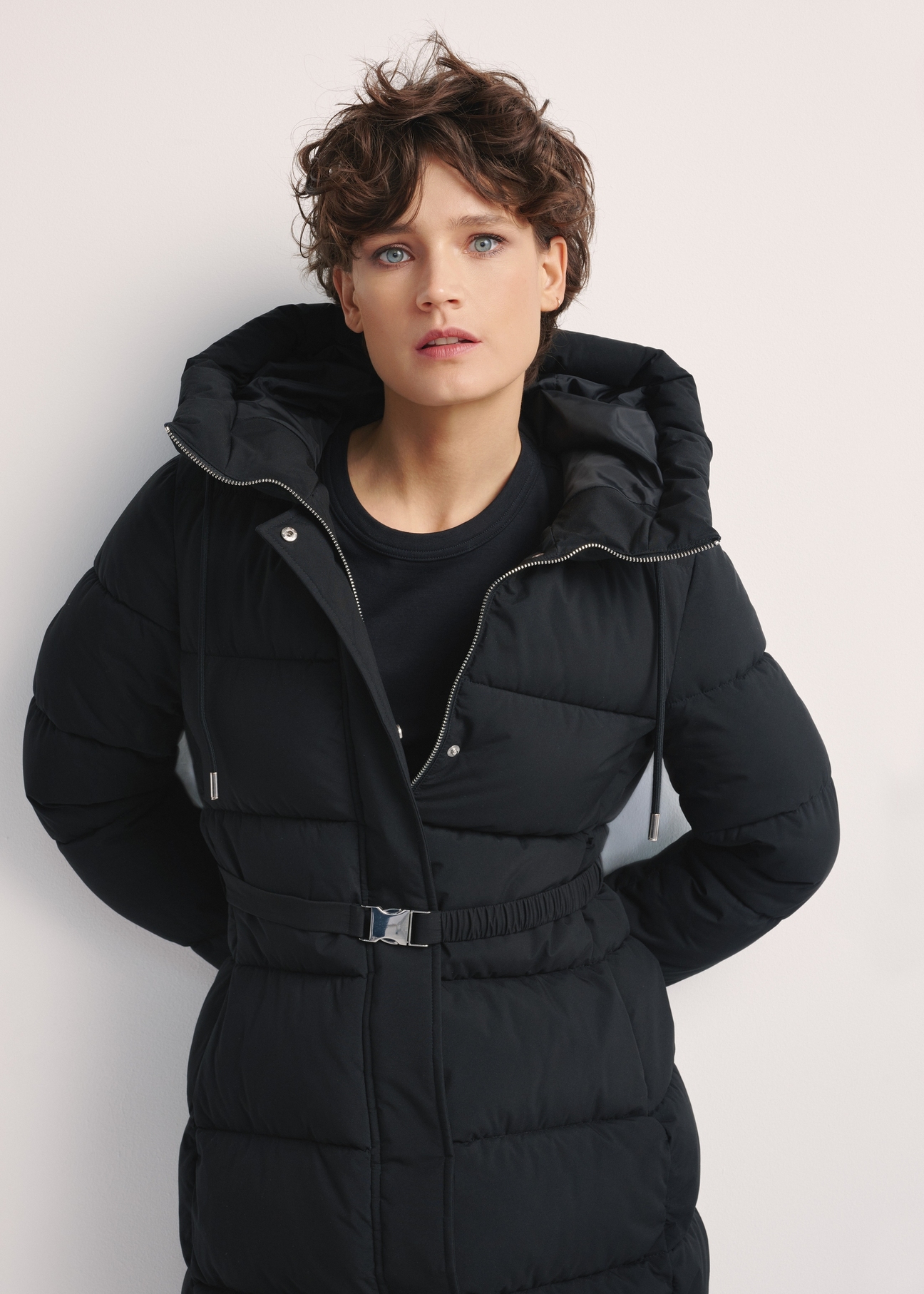 Long black women's jacket KURDT-0602-99(Z25), front view of the product on the model. Half of the silhouette visible.