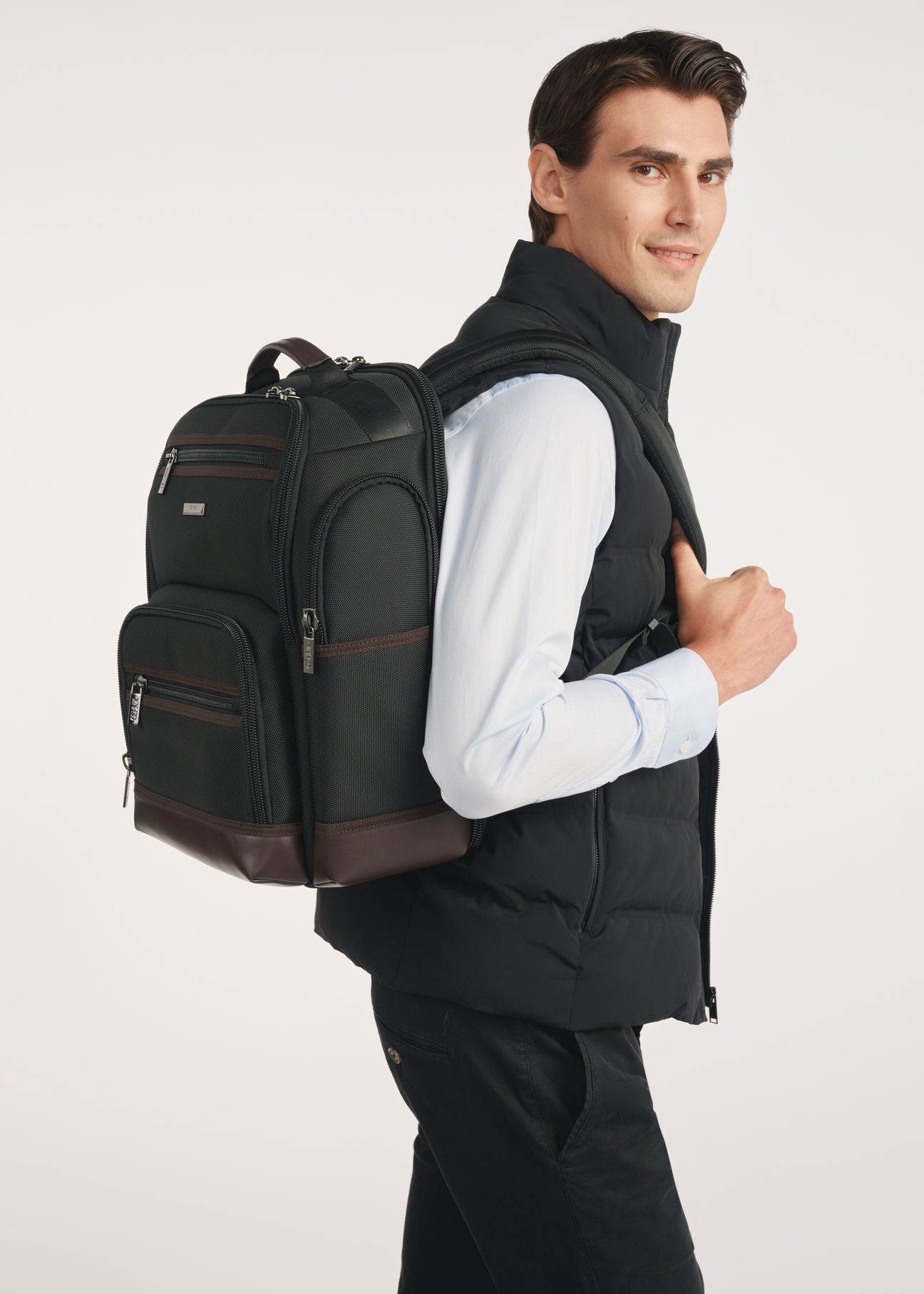 Black spacious men's backpack TORMN-0378-98(Z25), front view of the product on the model, half of the silhouette visible.