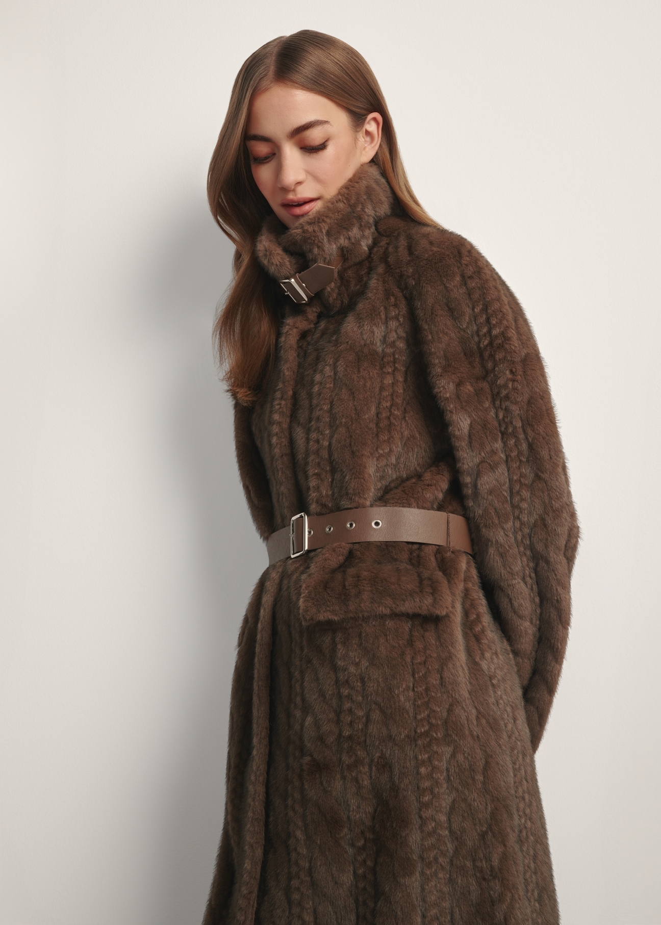 Women's long brown fur coat FUTDP-0065-89(Z25) - side view of the product on a model, against a white background. Half of the silhouette visible.