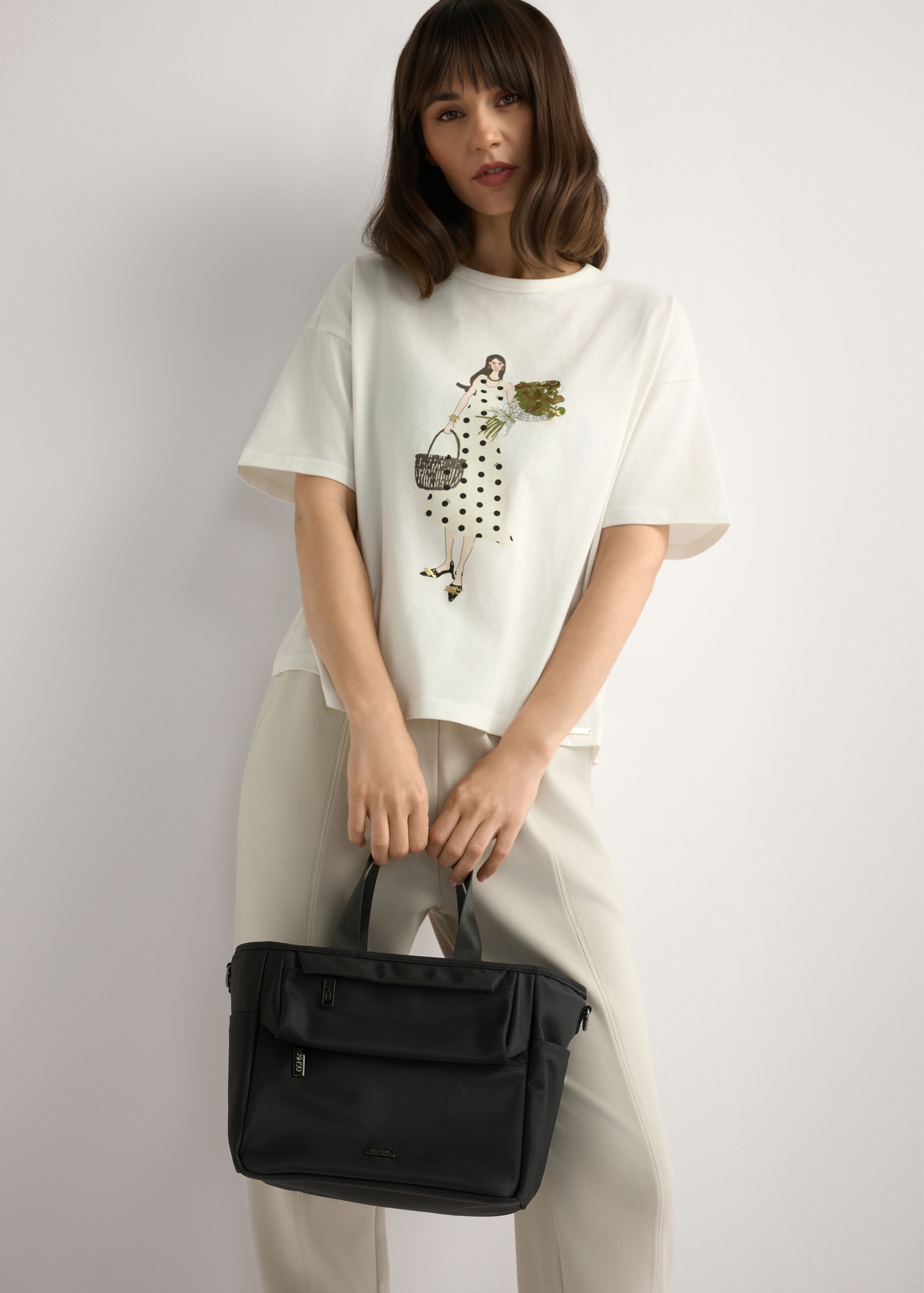 Black TOREN-0346-99(W26) lunchbox bag - view of the product held in the model's hand, against a light background. Knee-length silhouette visible.