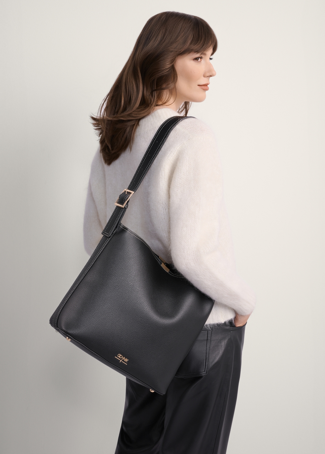 Black women's shoulder bag TOREC-1062-99(Z25), front view of the product on a model, half of the silhouette visible.