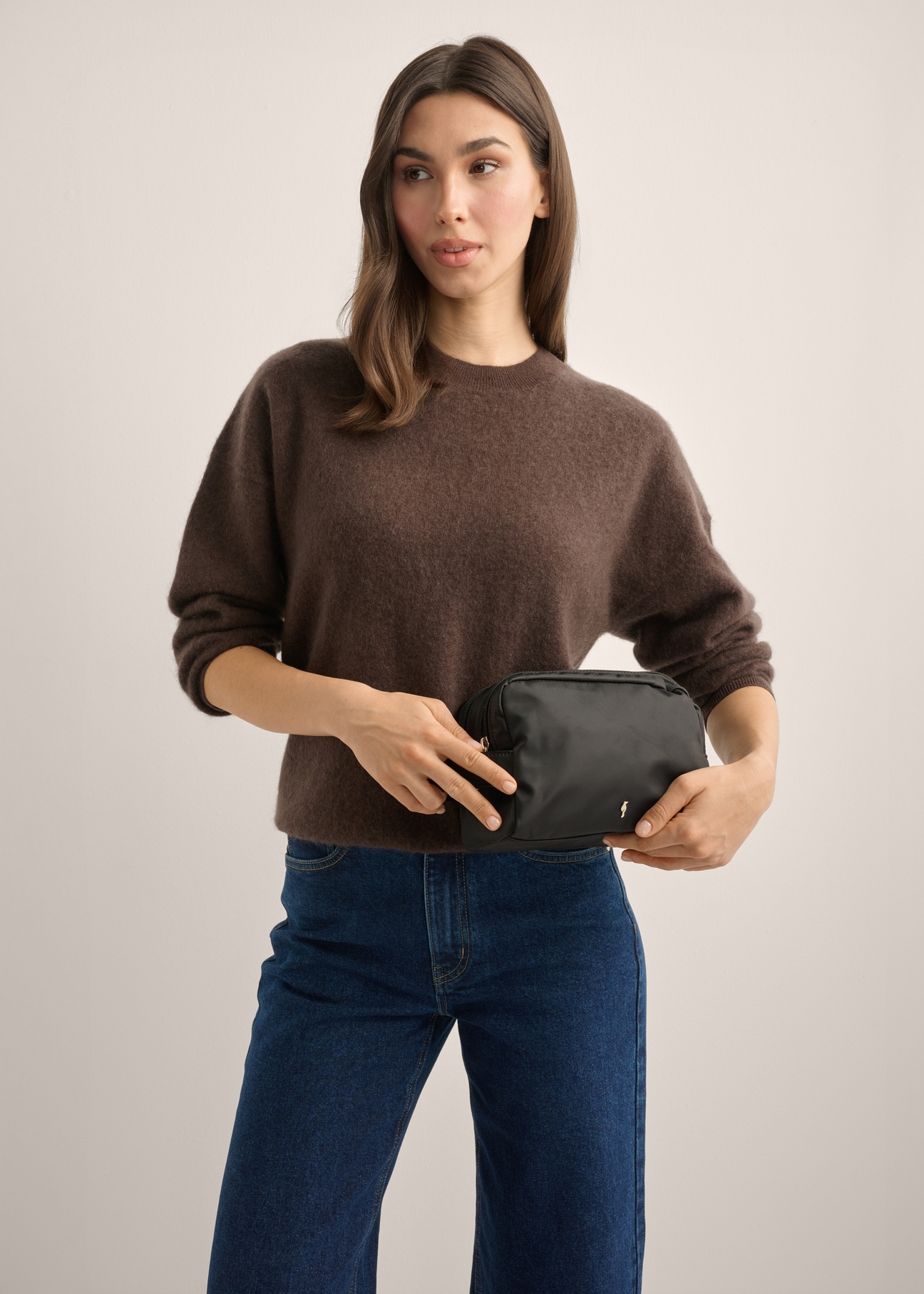 Black women's cosmetic bag TOREN-0348-99(Z26), diagonal view of the product on the model. Half of the silhouette visible.