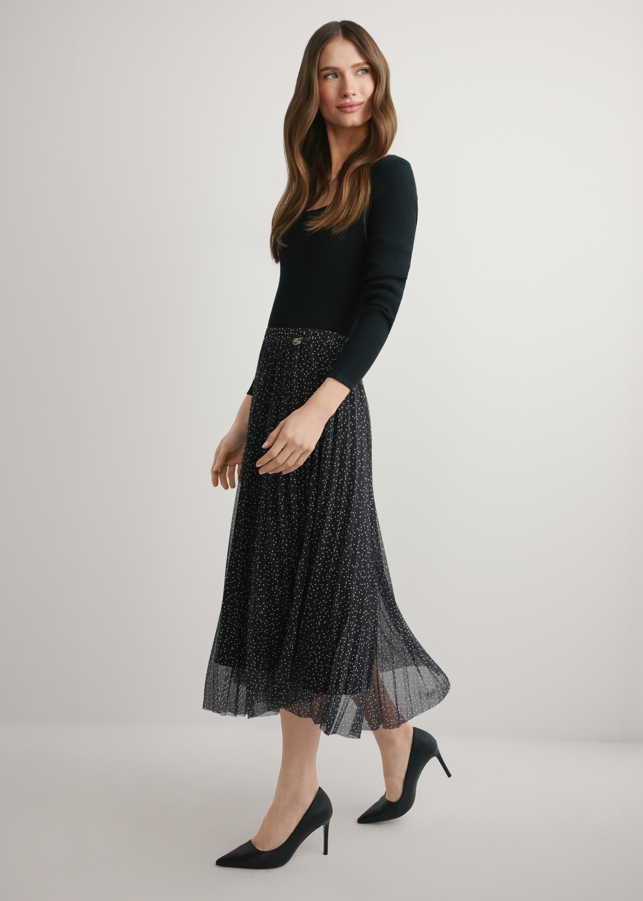 Pleated midi skirt with polka dots SPCDT-0110-9P(W26), product view from the side on the model, the whole silhouette is visible.