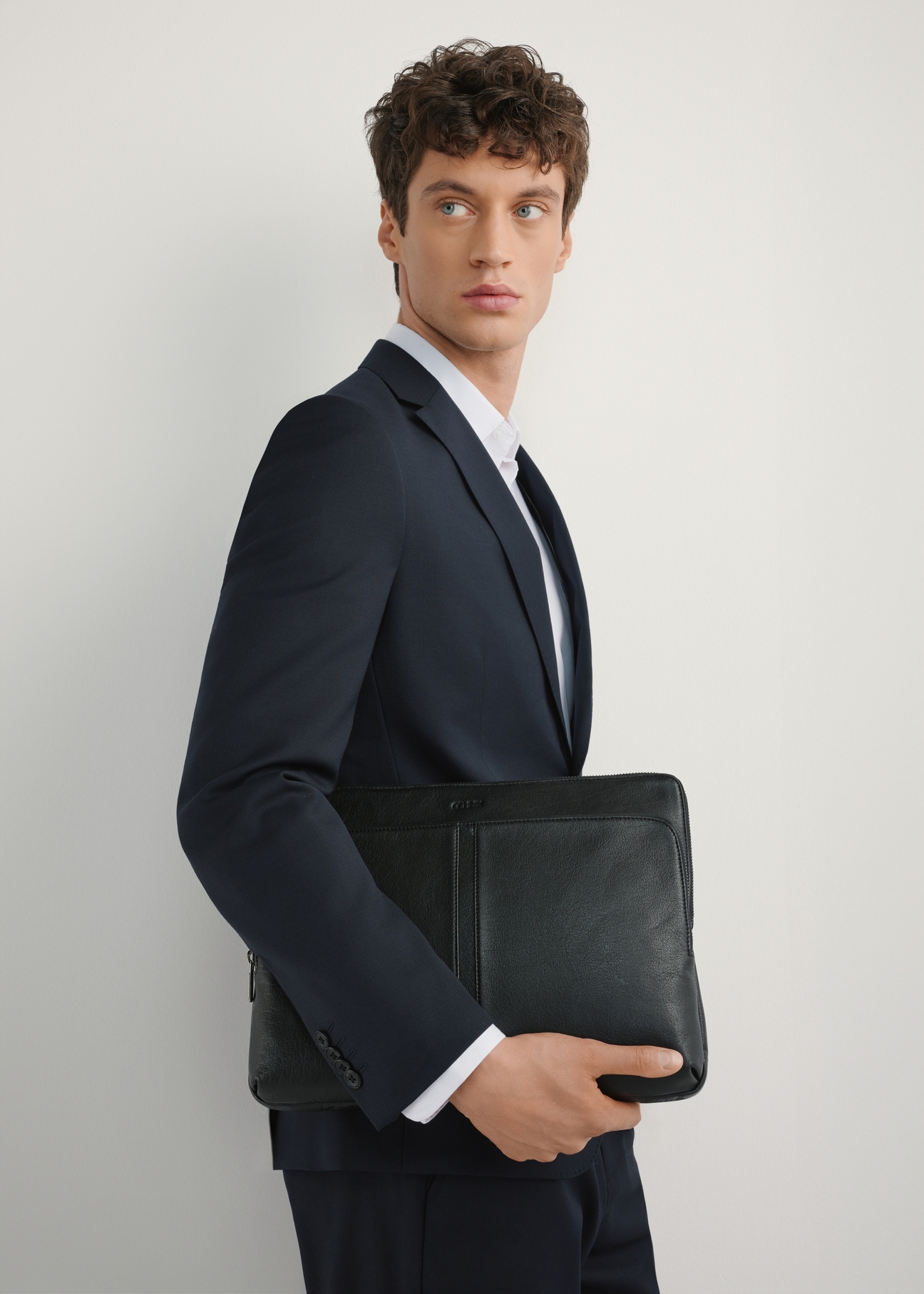 Black leather laptop briefcase TORMS-0455-99(W25), front view of the product on the model, half of the silhouette visible.