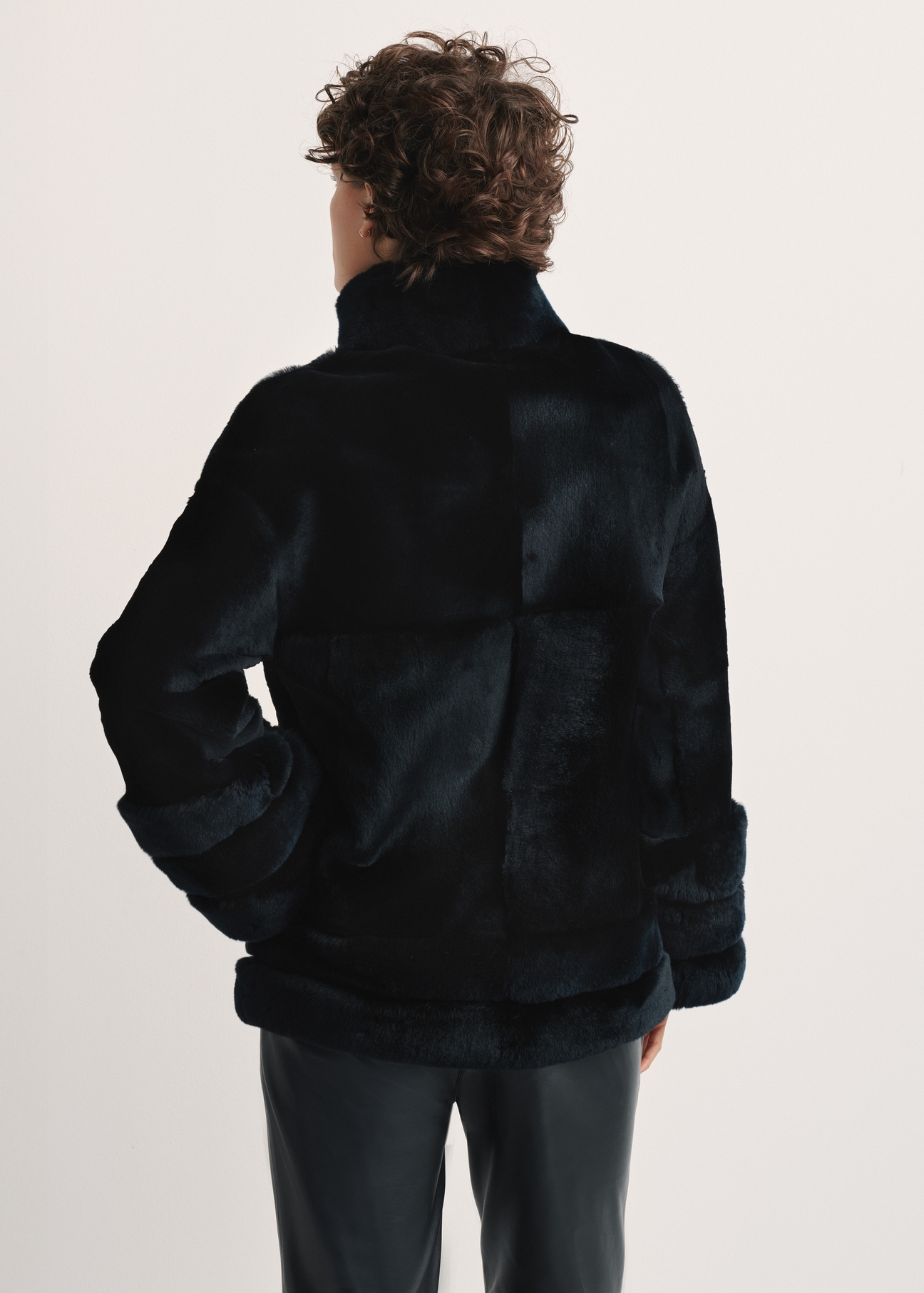 Black women's fur coat with a stand-up collar, natural FUTDF-0077-0984(Z24), back view of the product on a model, half of the silhouette visible.