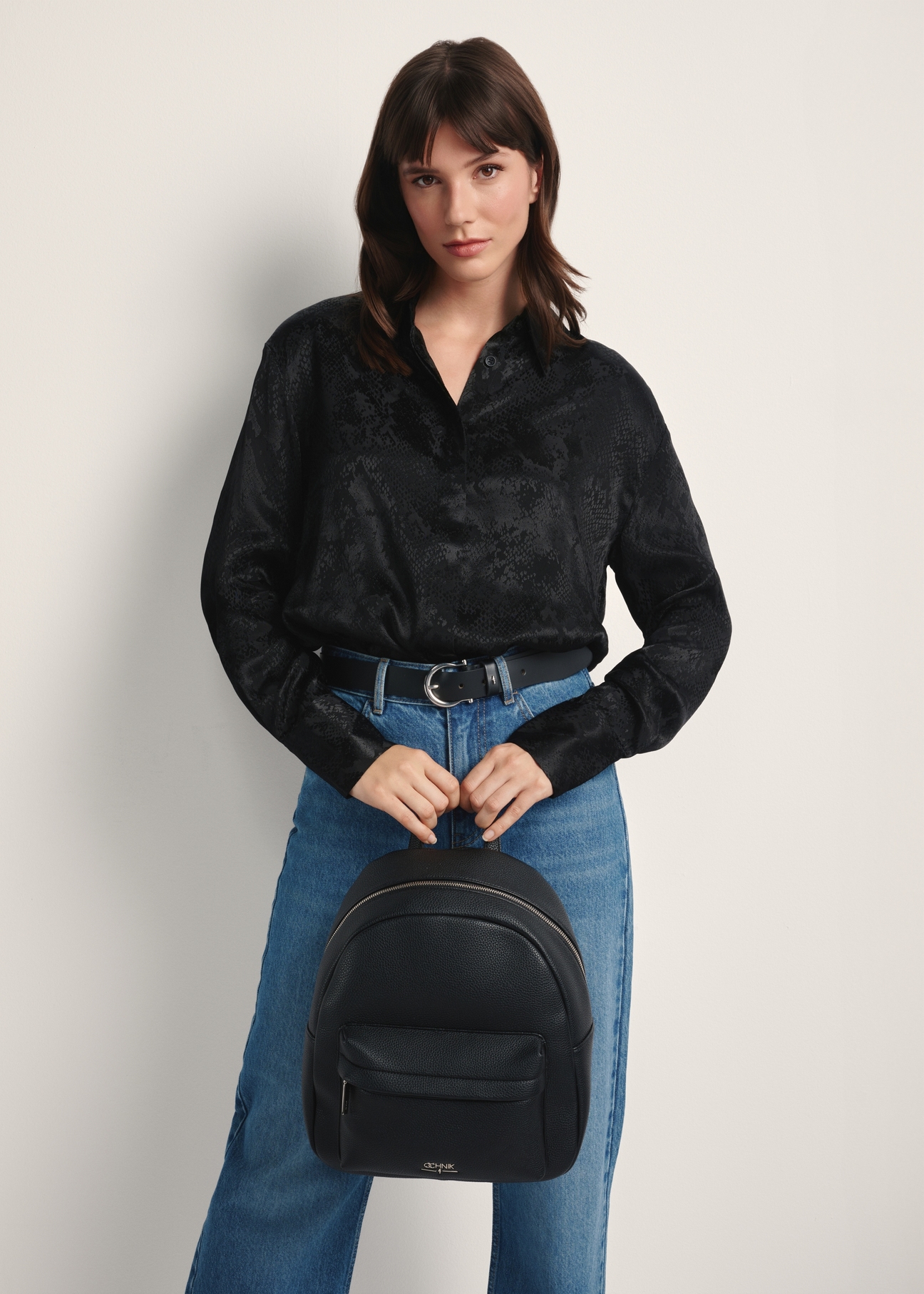 Black spacious women's backpack TOREC-1089-99(Z25) - front view of the product on a model against a white background. Knee-length silhouette visible.
