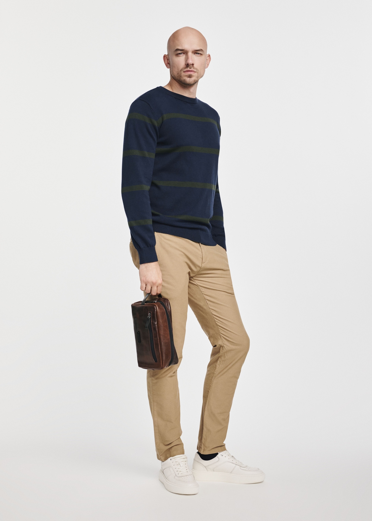 Men's brown leather cosmetic bag TORMS-0106-1H(W26), view of the product in the model's hand, on a light background.