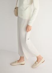 Women's cream leather moccasins with chain BUTYD-0914A-0B(W26), side view of the product on the model, half of the silhouette visible.