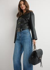 Black quilted women's backpack TOREC-1115-99(W26), view of the product in the model's hand, on a light background.