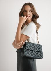 Black quilted women's handbag with chain TOREC-1117-99(W26), product view on model's shoulder. Half of silhouette visible.