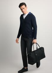 Black TORMN-0382-99(Z25) travel bag - diagonal view of the product, held by the model, against a light background. The entire silhouette is visible.