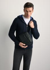 Black leather men's bag TORMS-0251B-99(Z25) - front view of the product, held by the model, against a light background. Knee-length silhouette visible.