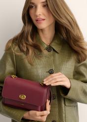 Small burgundy women's handbag with an elegant clasp TOREC-1322-4D(Z26), view of the product in the model's hands, on a light background.